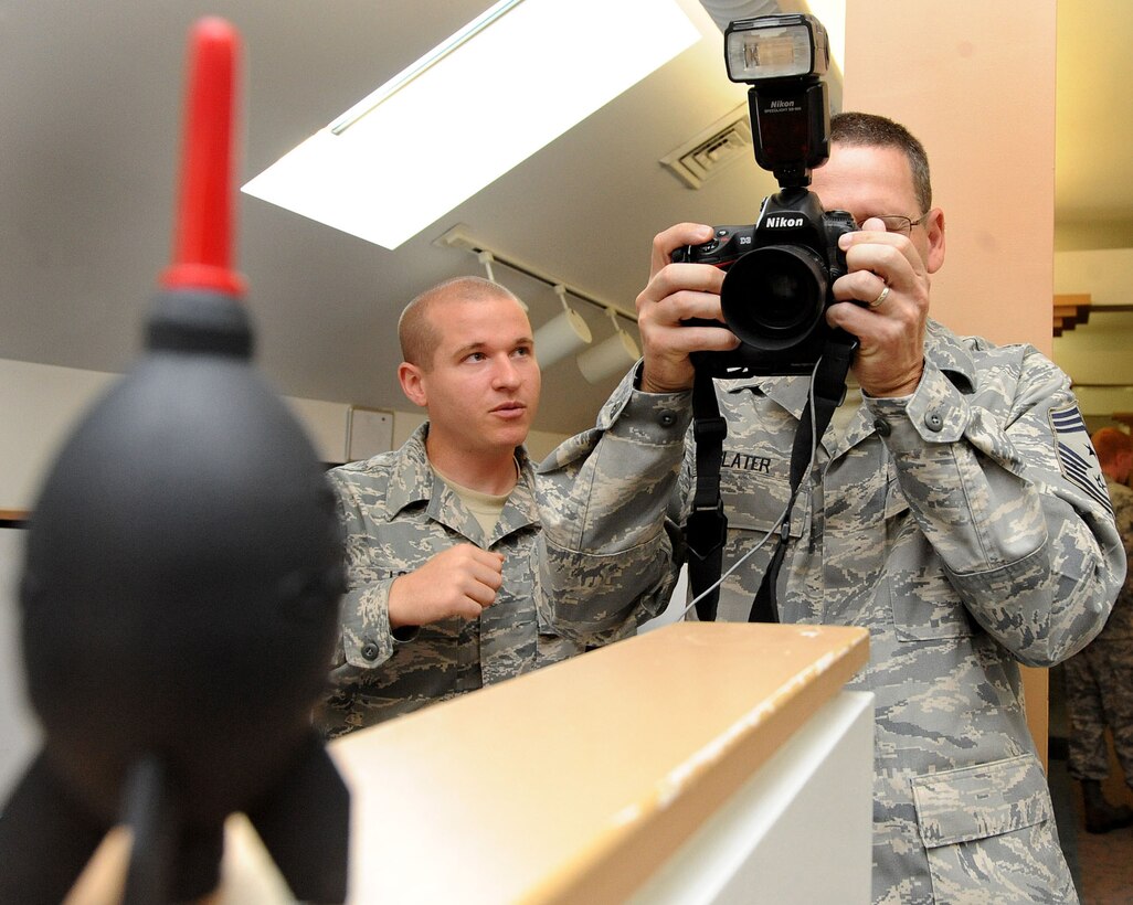 LANGLEY AIR FORCE BASE, Va. -- Chief Master Sgt. Kevin Slater, 1st Fighter Wing command chief, learns photography techniques from Staff Sgt. Barry Loo, 1st FW Public Affairs photographer, during his tour here Aug. 20.  Chief Slater learned basic tasks performed by photographers, broadcasters, and journalists during his tour of PA. (U.S. Air Force photo/Airman Rebecca Montez)