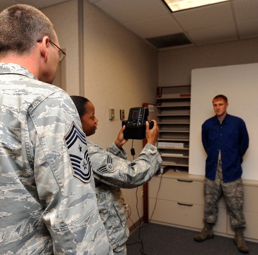 LANGLEY AIR FORCE BASE, Va. -- Chief Master Sgt. Kevin Slater, 1st Fighter Wing command chief, learns how to use a passport camera with the help of Senior Airman Dana Hill, 1st FW Public Affairs photographer, during his tour here Aug. 20.  Chief Slater learned basic tasks performed by photographers, broadcasters, and journalists during his tour of PA. (U.S. Air Force photo/Airman Rebecca Montez)