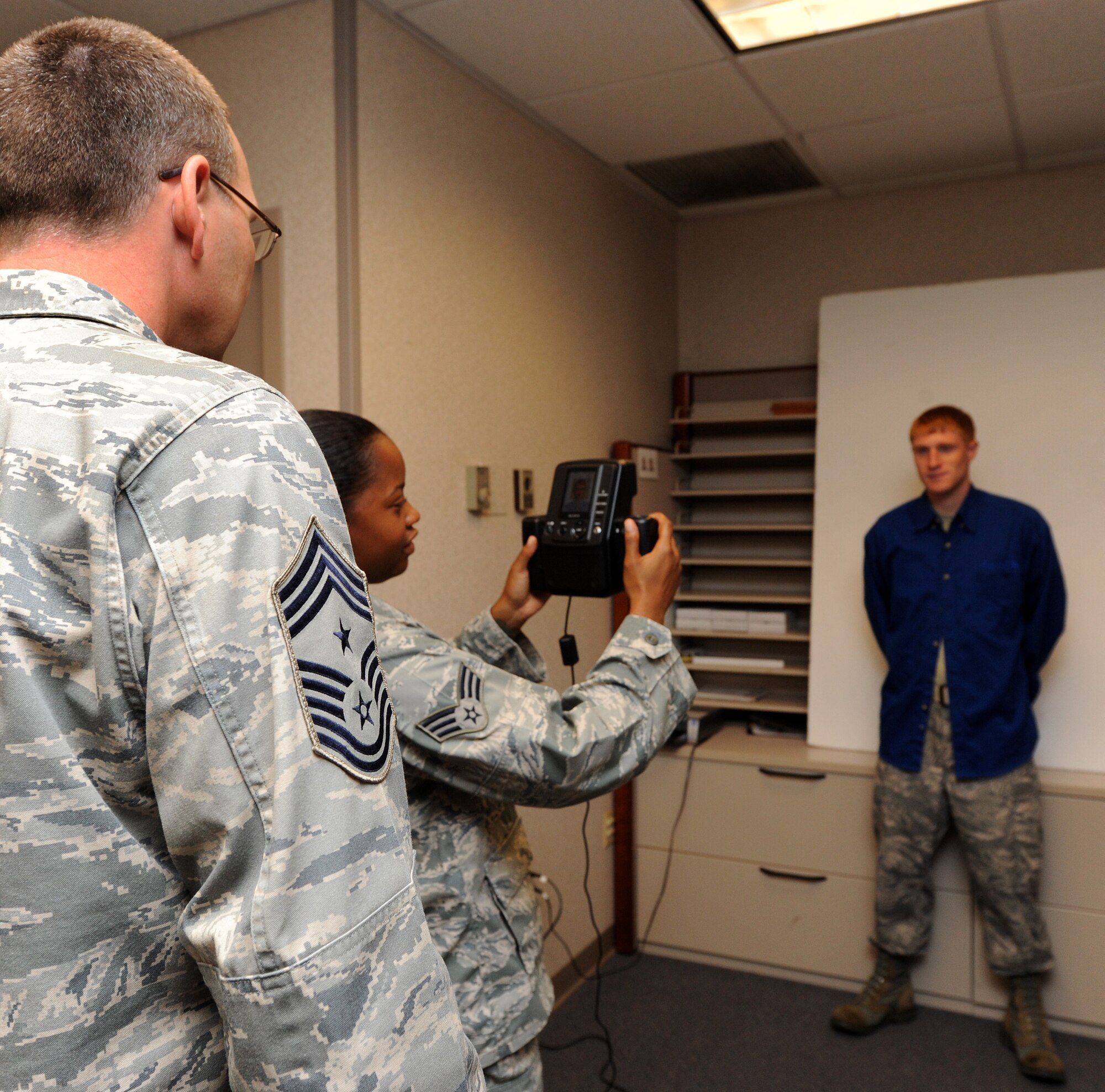 LANGLEY AIR FORCE BASE, Va. -- Chief Master Sgt. Kevin Slater, 1st Fighter Wing command chief, learns how to use a passport camera with the help of Senior Airman Dana Hill, 1st FW Public Affairs photographer, during his tour here Aug. 20.  Chief Slater learned basic tasks performed by photographers, broadcasters, and journalists during his tour of PA. (U.S. Air Force photo/Airman Rebecca Montez)
