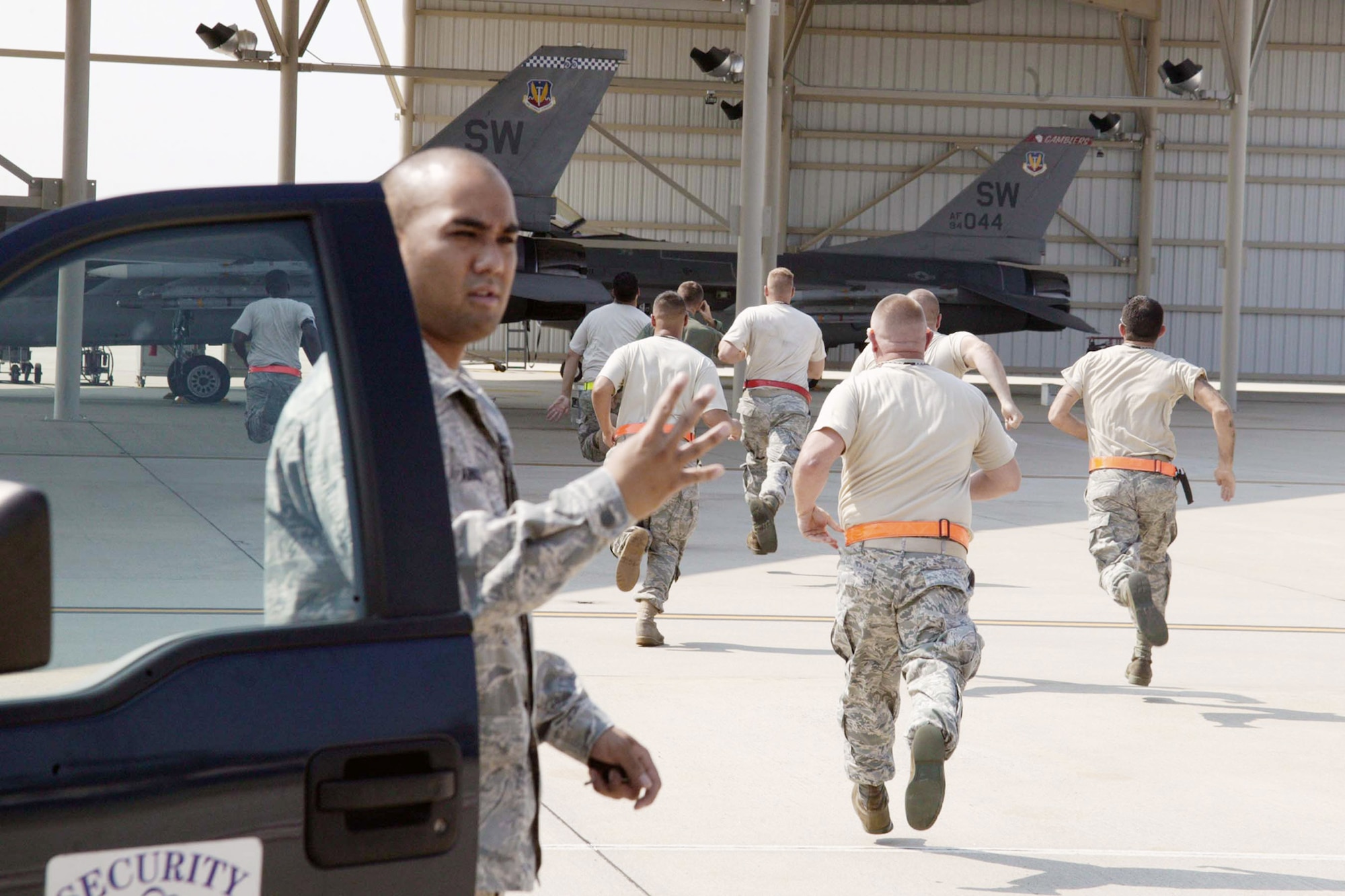Alert maintenance Airmen dash to their F-16 Fighting Falcons to prepare them for takeoff on a quick-reaction mission exercise while Airman Basic Julian Arnold checks badges to make sure everyone has proper access Aug. 11 at Shaw Air Force Base, S.C. The exercise, with cooperation from the Civil Air Patrol, provides interception training for Shaw AFB alert forces for real-world situations. Airman Arnold is assigned to the 20th Security Forces Squadron. (U.S. Air Force photo/Staff Sgt. John Gordinier) 
