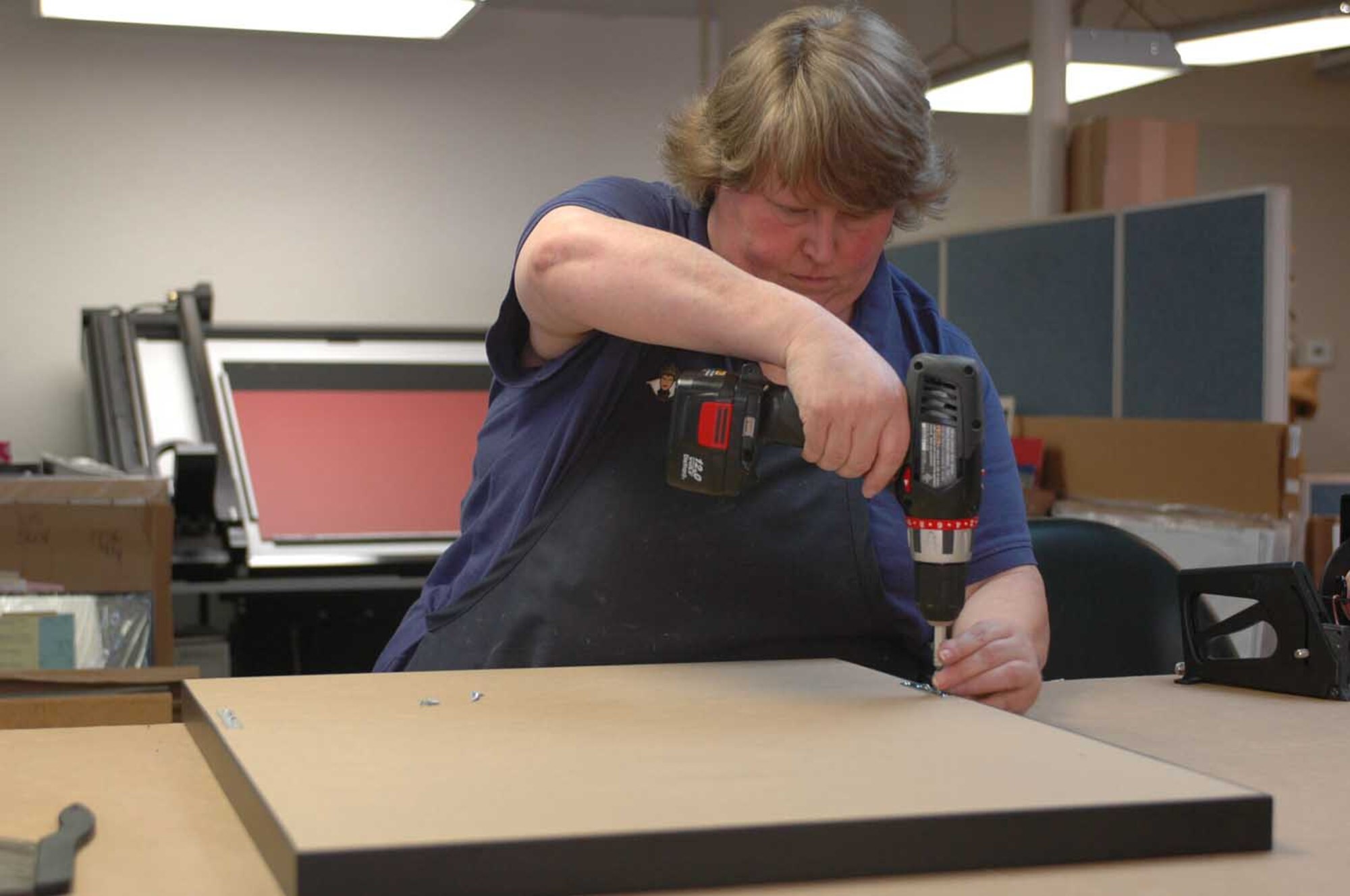 Rena Phillips screws the back of a framed concert poster Aug. 18, 2009, at the framing shop at the Travis’ Arts and Crafts Center. (U.S. Air Force photo/Nick DeCicco)