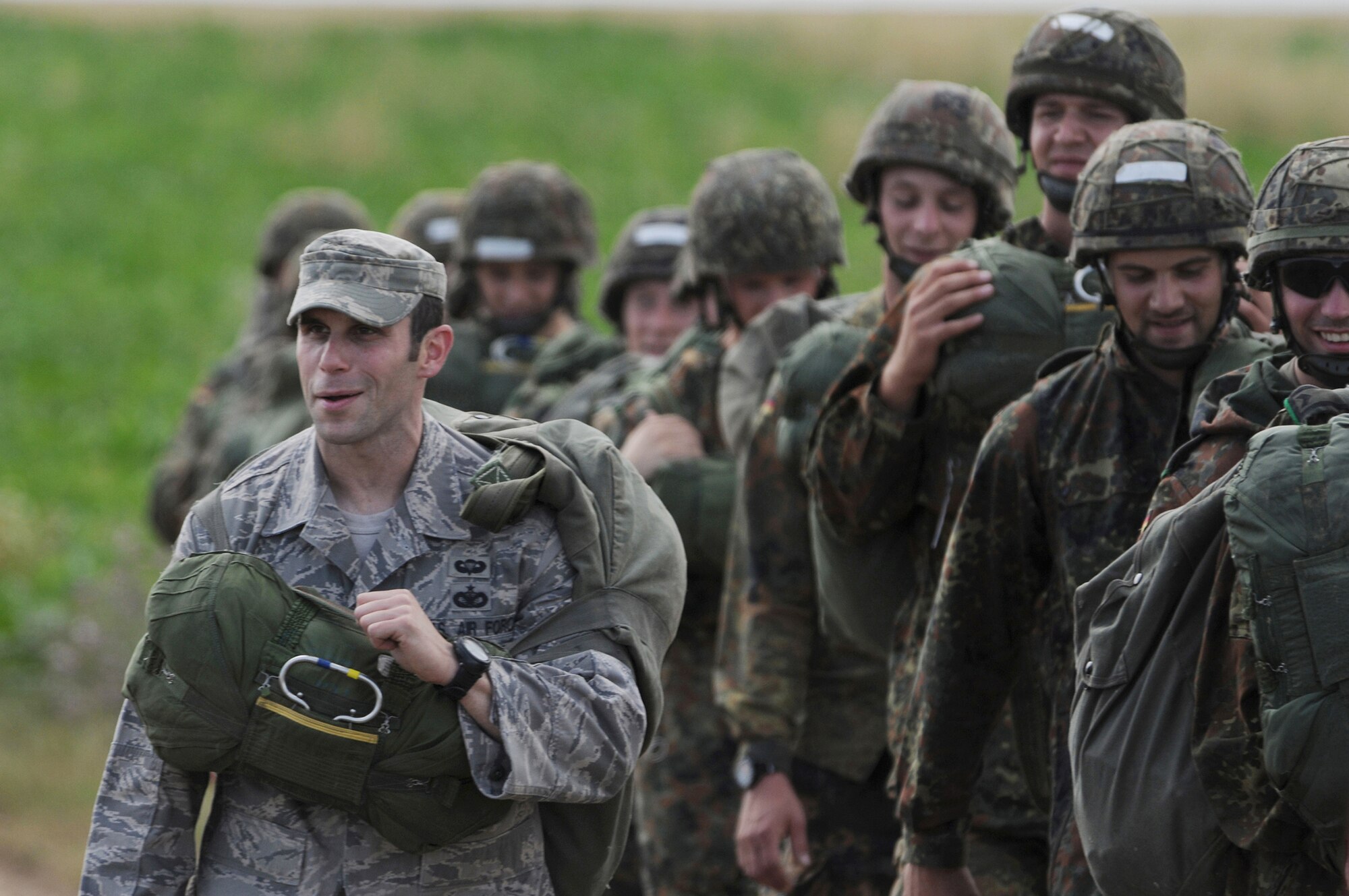 Staff Sgt. Joseph Klimaski walks off the field with German soldiers after landing at the Bunker drop zone Aug. 13 in southwestern Germany. U.S. Soldiers and Airmen performed a combined airborne jump with four other NATO countries during International Jump Week. Sergeant Klimaski is assigned to the 435th Security Forces Squadron. (U.S. Air Force photo/Airman 1st Class Grovert Fuentes-Contreras) 