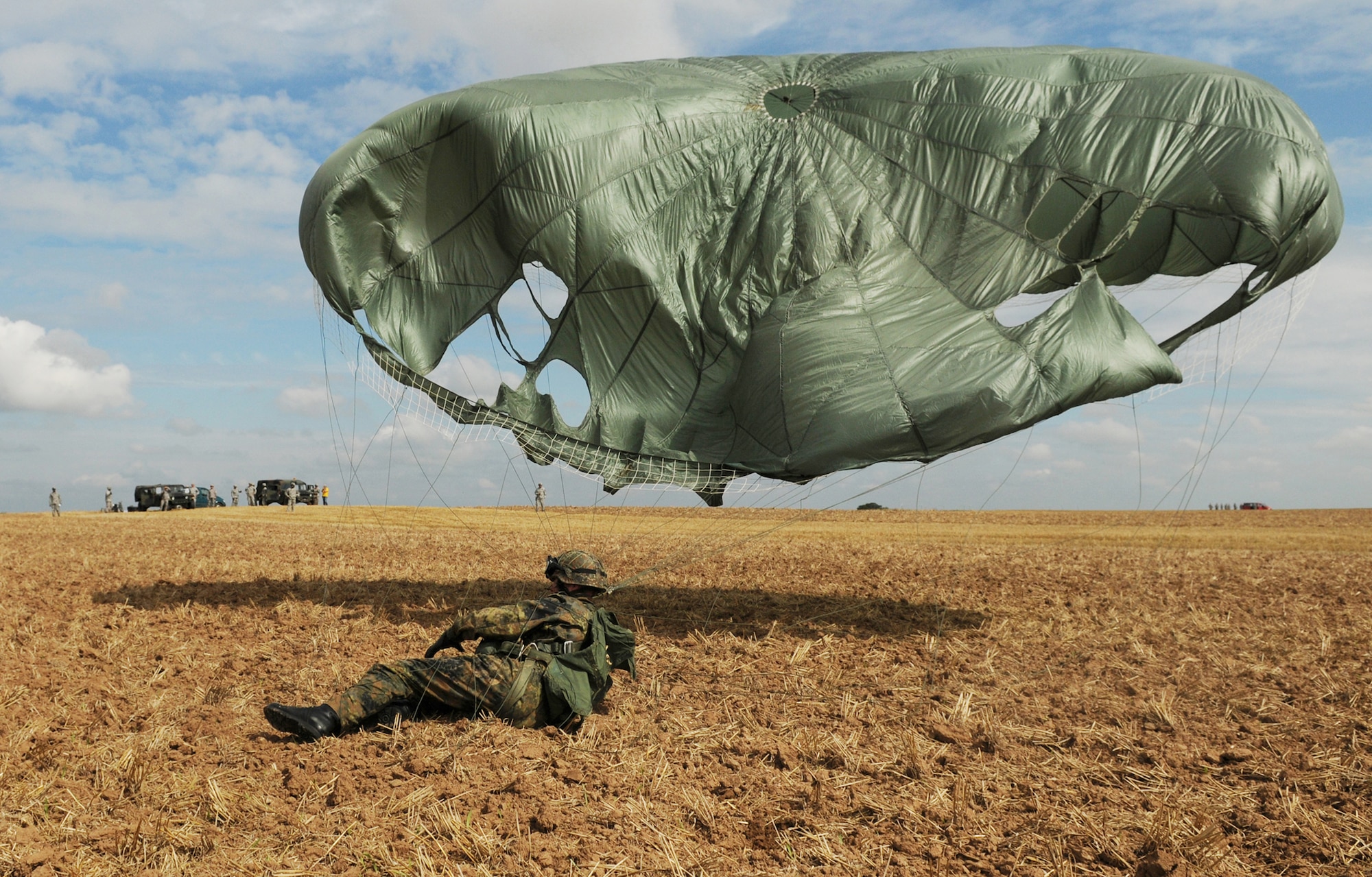 German army soldier Christian Schlueter lands after parachuting out of a C-130 Hercules on the Bunker drop zone Aug. 13 in southwestern Germany. U.S. Soldiers and Airmen performed a combined airborne drop with four other NATO countries during International Jump Week. (U.S. Air Force photo/Airman 1st Class Grovert Fuentes-Contreras) 