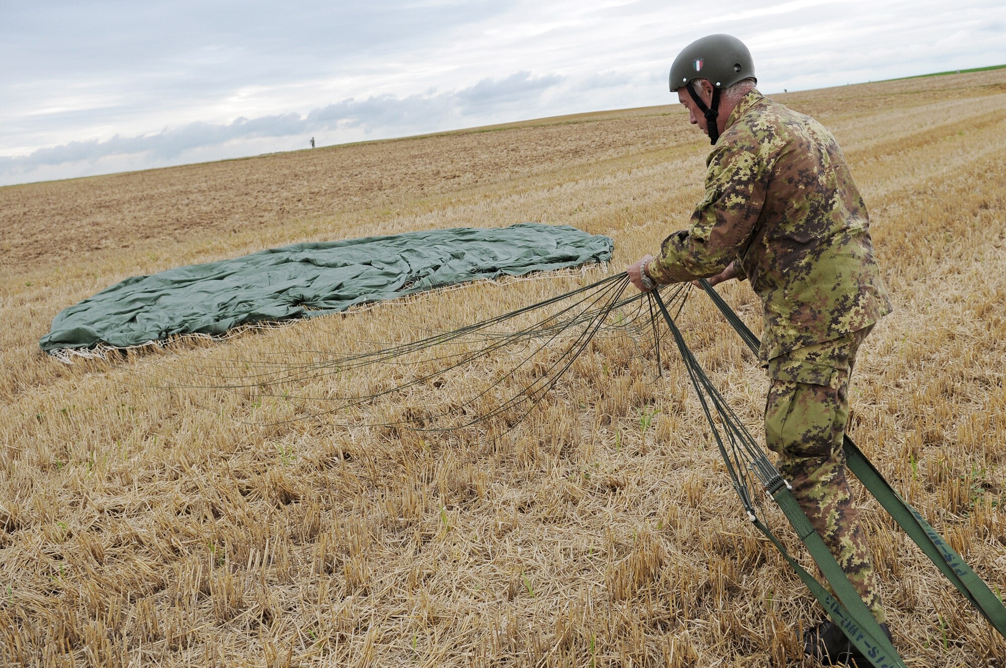 Italian Army soldier Giovanni Cacciari packs his parachute after landing Aug. 13 at the Bunker drop zone in southwestern Germany. U.S. soldiers and Airmen did a combined airborne drop with four other NATO countries. German, Italian, Belgium, and Dutch Armies attended the airborne drop officially called International Jump Week. (U.S. Air Force photo/Airman 1st Class Grovert Fuentes-Contreras) 