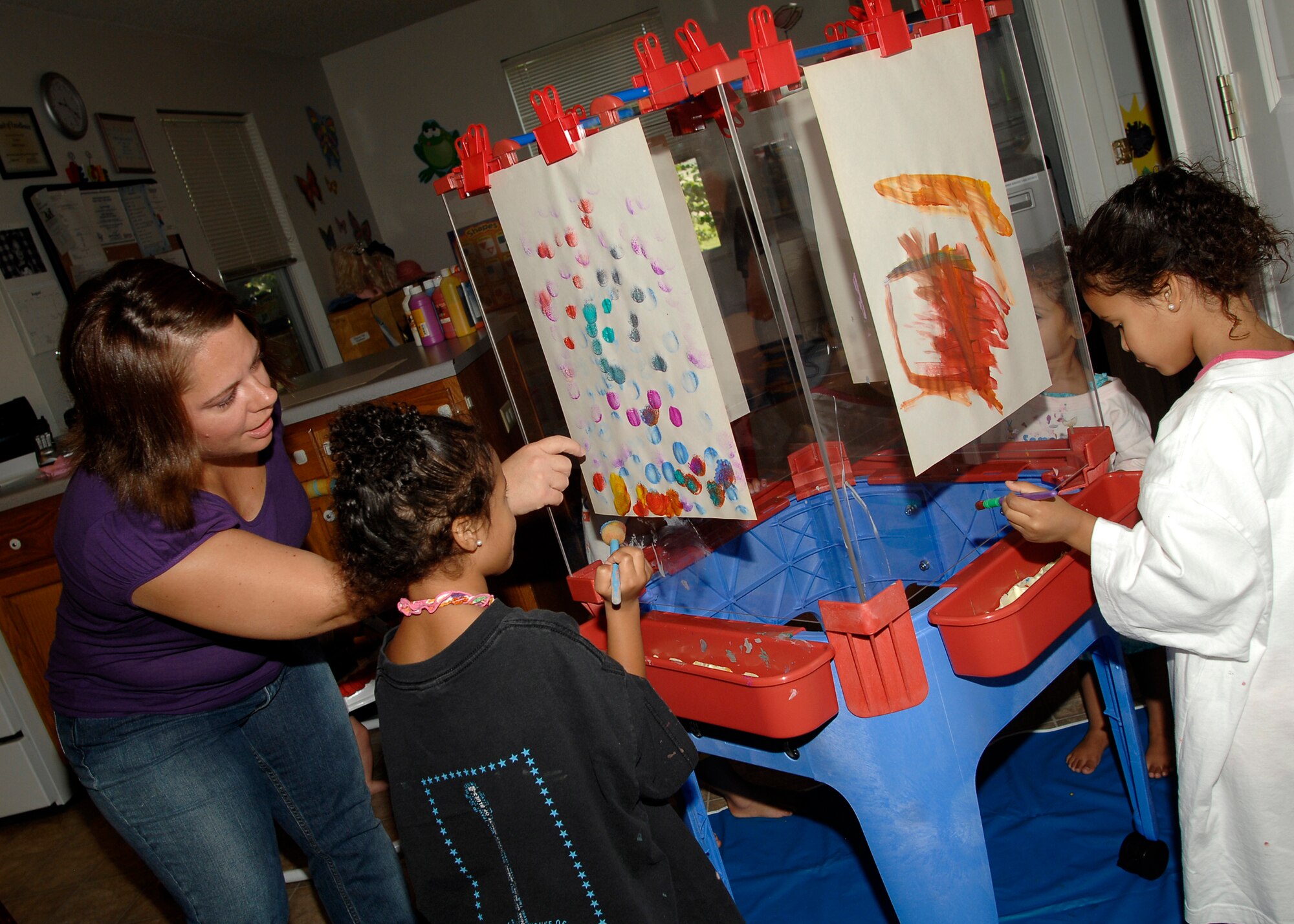 Julie Cavazos, an at-home family care provider, teaches Cloe Lewis, 4, how to paint in Cavazos’s home on Aug. 13. Cavazos has been a family care provider at McConnell Air Force Base, Kan., for two years.  (U.S. Air Force photo/Senior Airman Anthony Mejia)