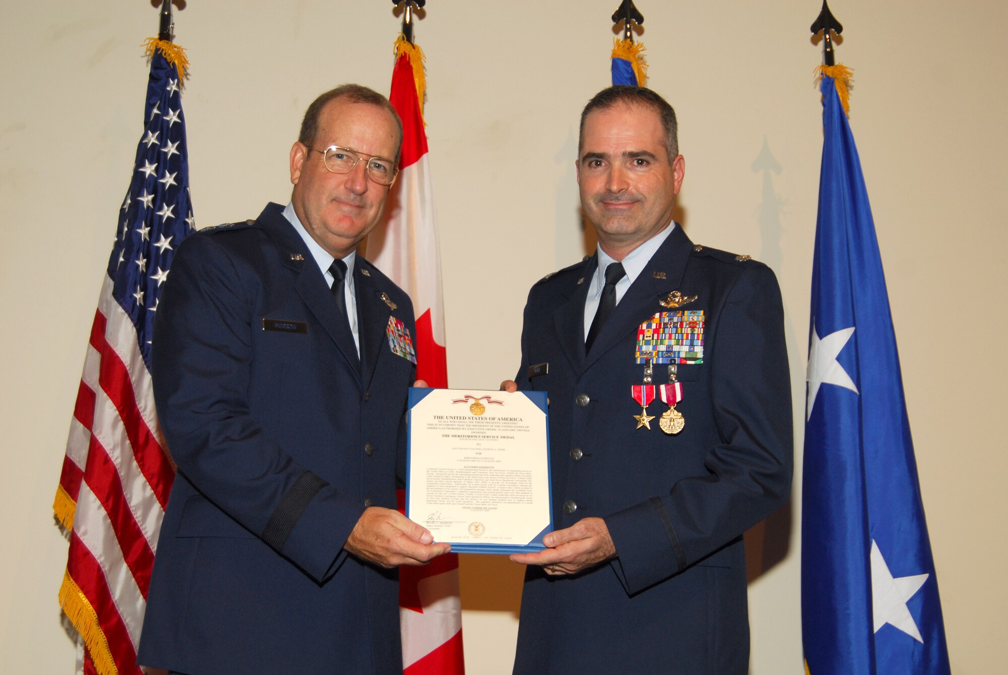 Maj. Gen. Hank Morrow, 1st Air Force commander, presents Col. George Uribe, 1st Air Force chief of Standardization and Evaluation, with the Meritorious Service Medal during a ceremony recognizing Col. Uribe's accomplishments with 1st AF.  Uribe was also presented with the Bronze Star Medal, his fourteenth Air Medal, and promoted to Colonel.  (U.S. Air Force photo by Lisa Norman)