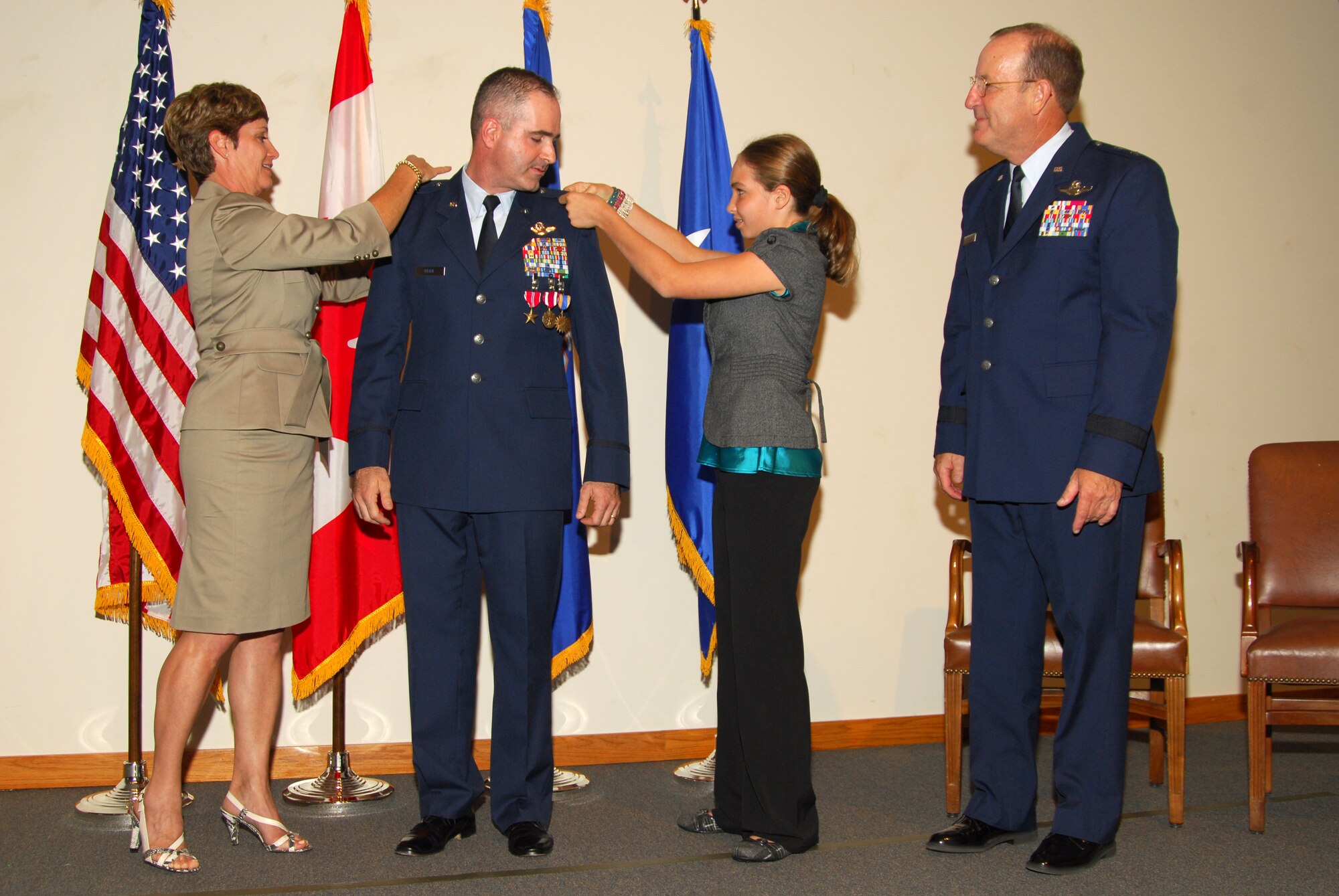 Col. George Uribe,  1st Air Force chief of Standardization and Evaluation, looks on as his wife, Rita and daughter, Katie pin on his new silver eagles during his promotion ceremony as Maj. Gen. Hank Morrow, 1st Air Force commander, looks on. Col Uribe was also presented with the Bronze Star Medal, the Meritorious Service Medal, and his fourteenth Air Medal. (U.S. Air Force photo by Lisa Norman)