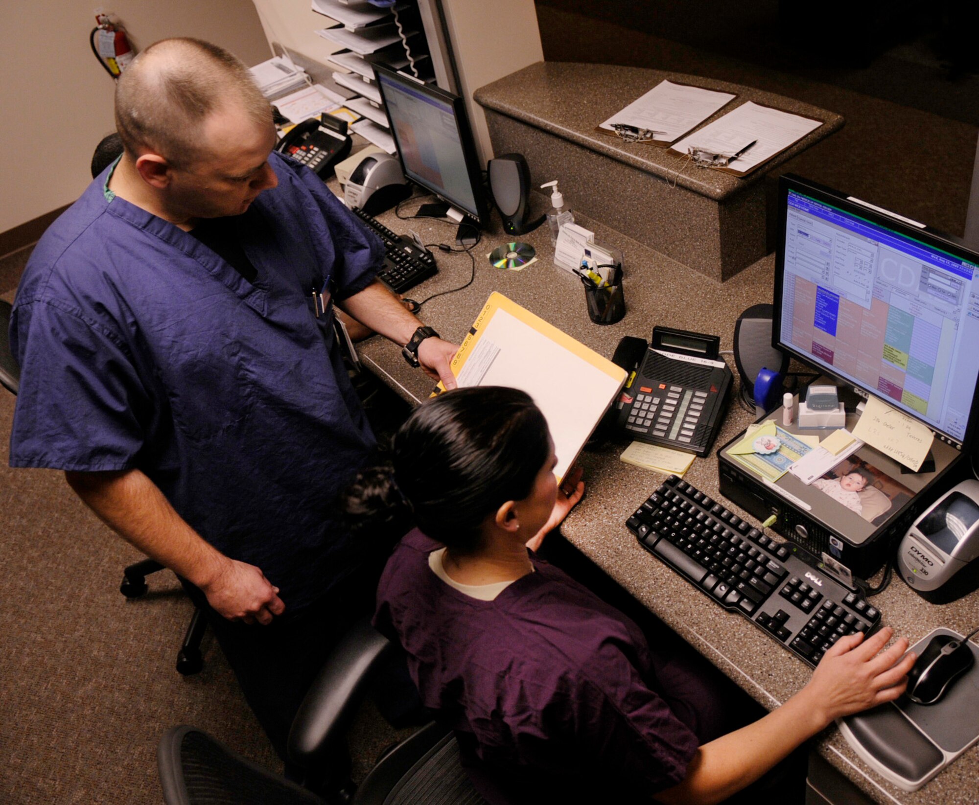 Master Sgt. Patrick McGonagill reads a chart for Tech. Sgt. Jenifer Dreier Aug. 19, 2009, Eielson Air Force Base, Alaska. The sergeant's maintain patient appointments, order supplies, and scheduling. Sergeant's McGonagill and Dreier are dental technicians assigned to the 354th Medical Group. (U.S. Air Force photo/Airman 1st Class Laura Goodgame)