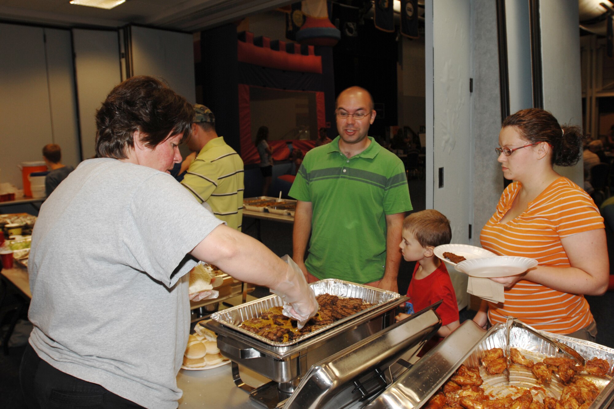 Lesley Hall, 22nd Force Support Squadron, serves food to Staff Sgt. William Morris, 22nd Aircraft Maintenance Squadron, his wife Monica, and son Ephraim, 4, during Family Night at McConnell Air Force Base, Kan. on Aug. 14. (U.S. Air Force photo/Staff Sgt. Jamie Train)