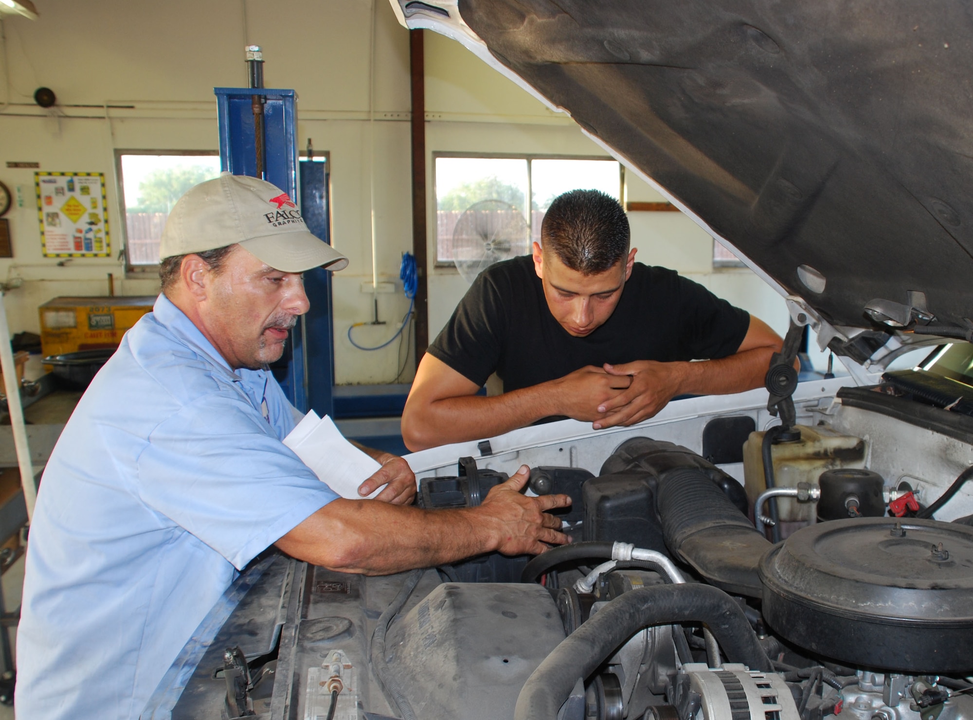 Senior Airman Tony Vitela listens as auto skills center mechanic Scott Ficken teaches Car Care 101 Aug. 14. The class is designed for the those with little to no knowledge of automobiles and basic maintenance. (U.S. Air Force photo/ Airman 1st Class Matthew Varga)