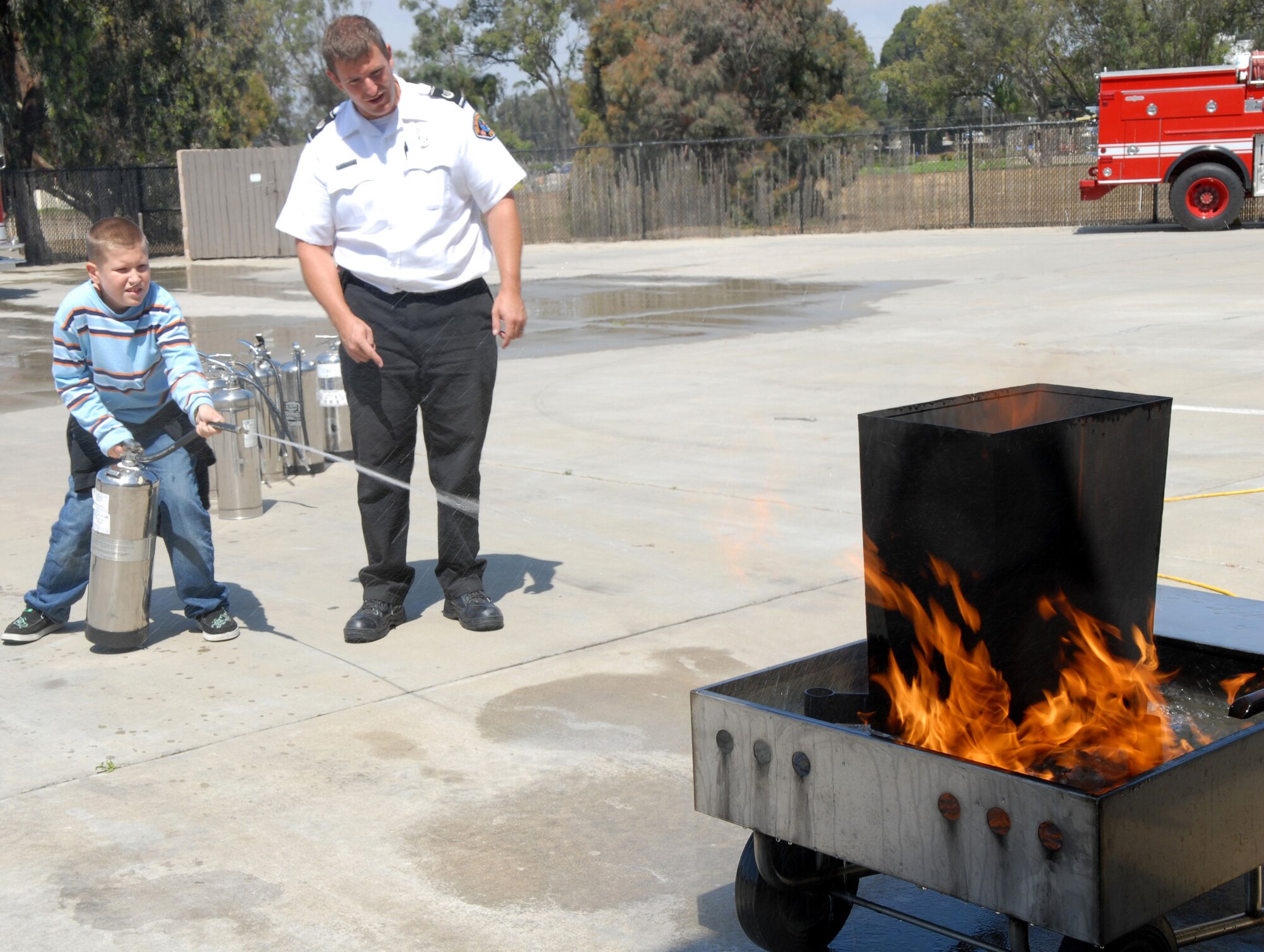 VANDENBERG AIR FORCE BASE, Calif. -- Teaching the "pull, aim, squeeze, sweep" method, Scott Balatgek, who is a 30th Civil Engineer Squadron fire inspector, teaches a Kids’ Fire Camp attendee how to use a fire extinguisher Aug. 15 at Fire Station 2 here. Besides fire extinguisher training, the children also had a chance to take a station tour to learn where and how firefighters live during their 24-hour shifts; receive smoke and fire safety training; and run an obstacle course that gave them a chance to use firefighter tools. (U.S. Air Force photo/Airman 1st Class Kerelin Molina)