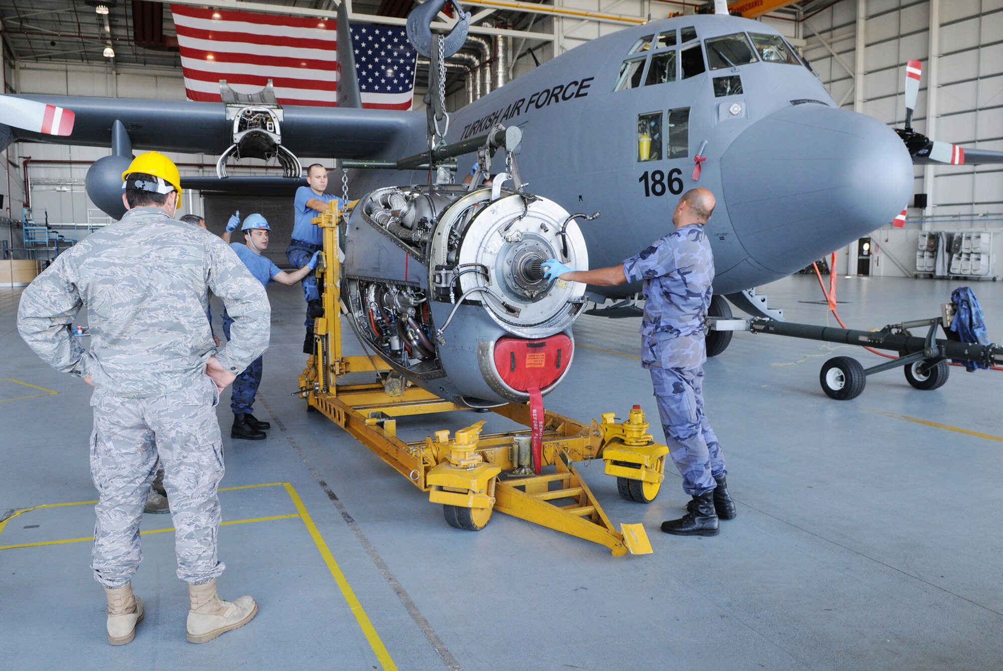 Turkish air force maintainers work with U.S. Air Force Airmen to remove a damaged engine from a Turkish C-130 Aug. 17 at Royal Air Force Mildenhall, England. Airmen from the 100th Maintenance Squadron lent their facilities and equipment to the maintainers, who were flown in from Turkey after a post-flight inspection revealed problems with the engine, temporarily grounding it. (U.S. Air Force photo/Staff Sgt. Austin M. May)
