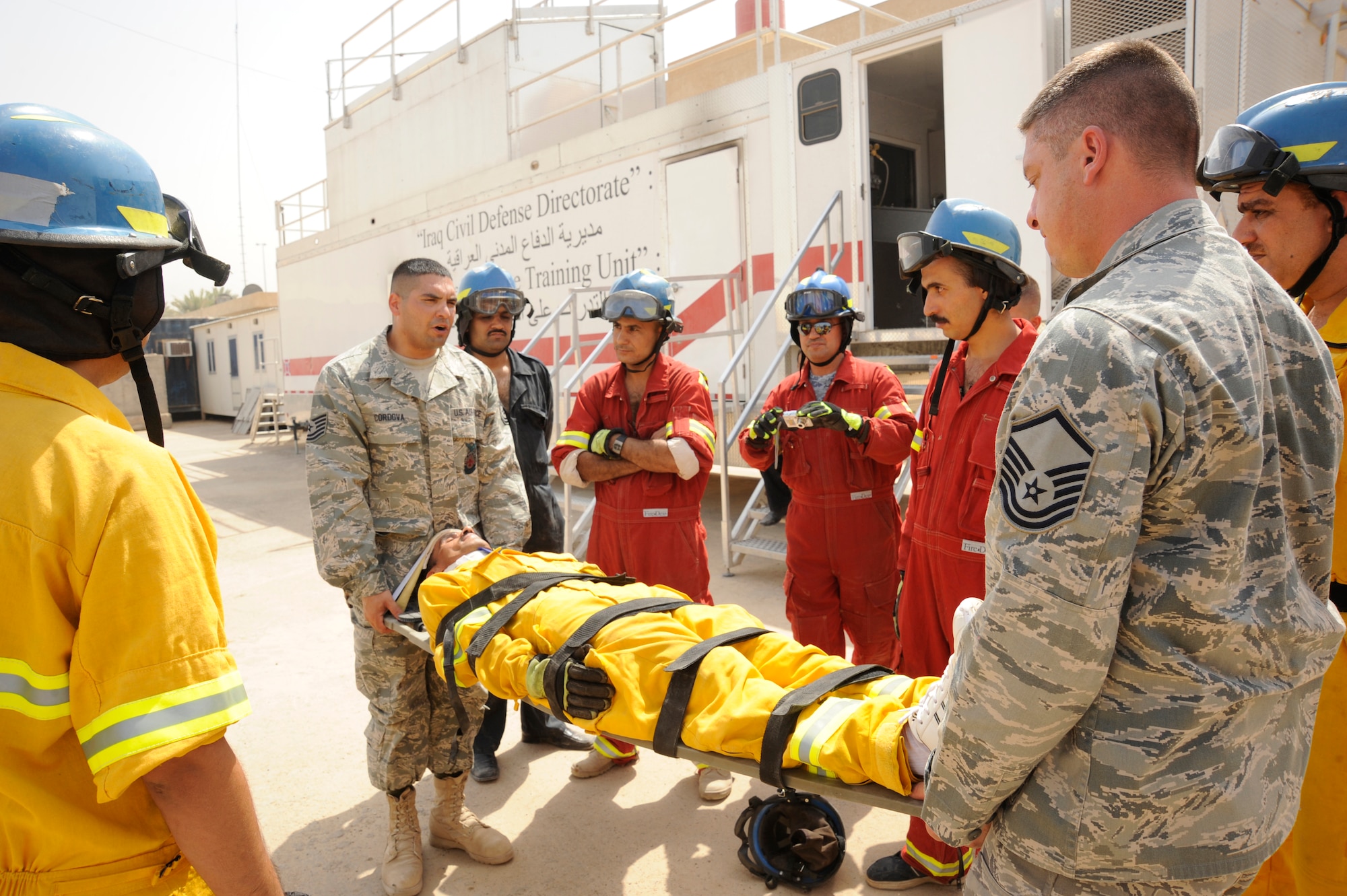 BAGHDAD, Iraq -- Tech. Sgt. Essam Cordova (left) and Air Force Master Sgt. Jeffrey Kimball (right), 821st Expeditionary Training Squadron fire and rescue advisors, instruct Iraqi firefighter students how to properly move a patient secured to a long spine board for emergency services here Aug. 9, 2009. They teach procedures in advanced rescue with auto extrication to students in the International Zone. Sergeant Cordova and Kimball are both deployed from Goodfellow Air Force Base, Texas. Sergeant Cordova is a native of Queens, N.Y., and Sergeant Kimball is from Pittsfield, N.H.  (U.S. Air Force photo/Tech. Sgt. Johnny L. Saldivar/Released)