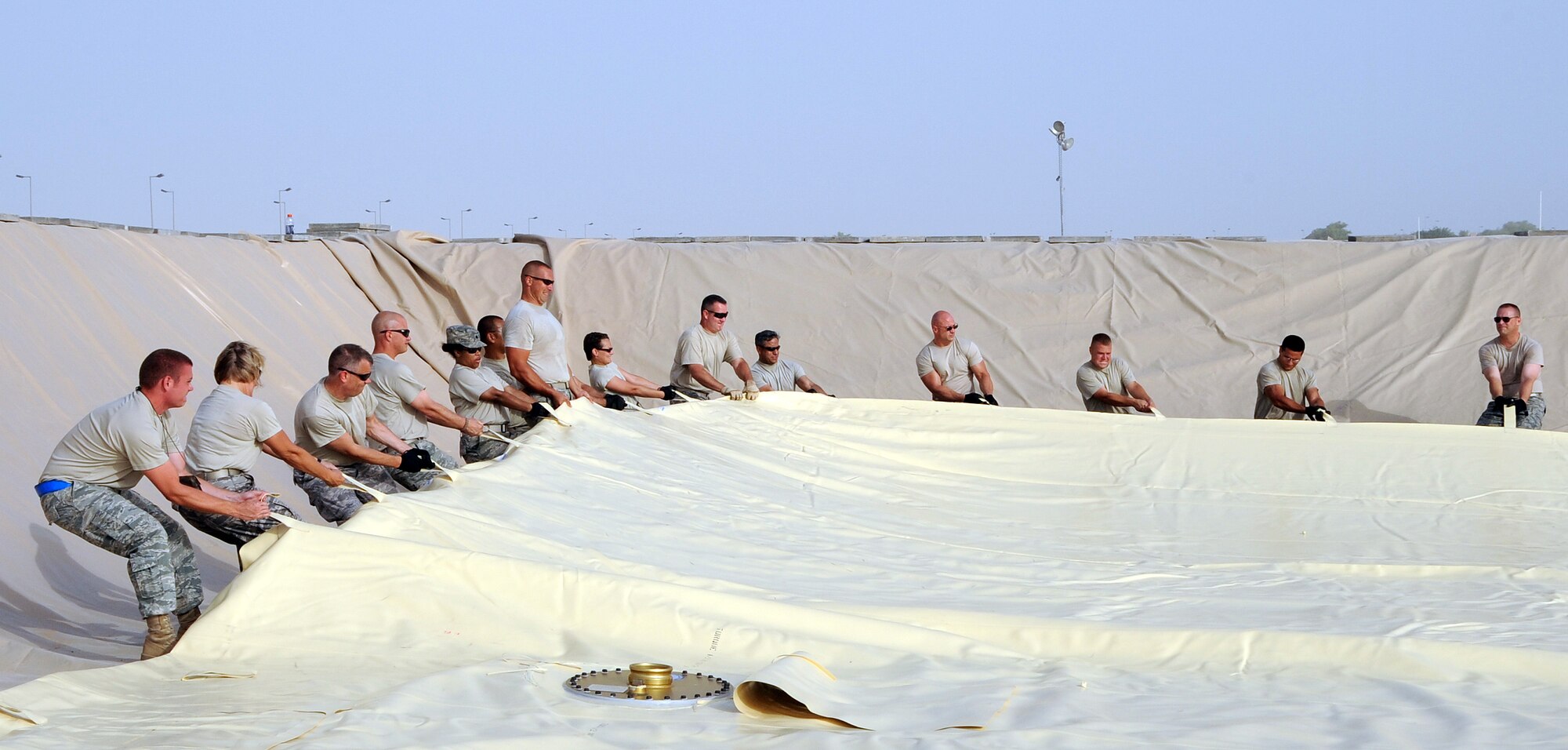 SOUTHWEST ASIA - Members of the 380th Air Expeditionary Wing work together to move a large JP-8 fuel bladder into place Aug. 18. The team of workers included volunteers from the 380th AEW Staff and 380th Expeditionary Mission Support Group. (U.S. Air Force photo/Tech. Sgt. Charles Larkin Sr)