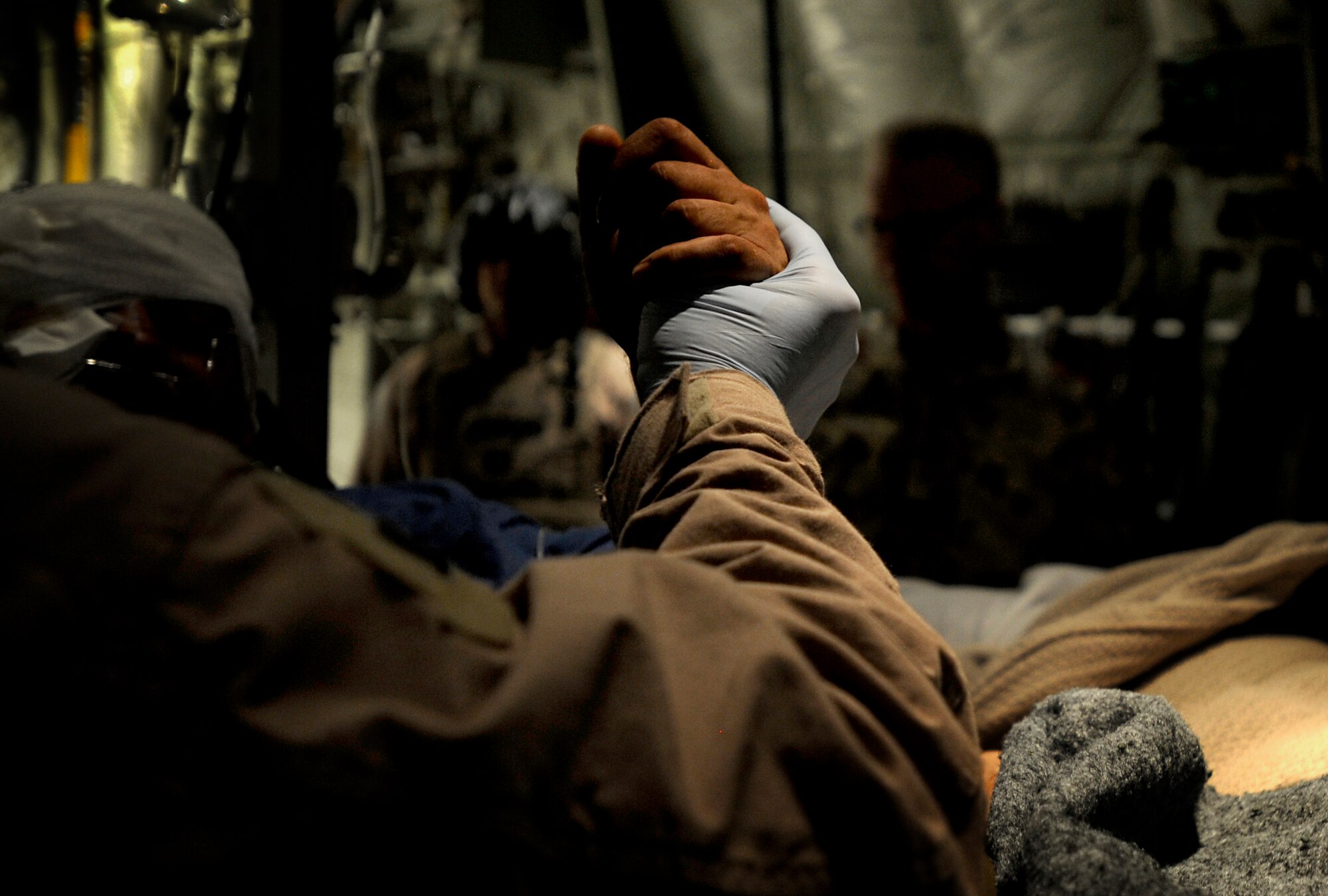 U.S. Air Force Airman, 451st Expeditionary Aeromedical Evacuation Flight, holds the hand of a patient during an Aeromedical Evacuation mission to transport patients from Kandahar Air Field to Bagram Air Base July 19, Kandahar Air Field, Afghanistan. (U.S. Air Force Photo by Staff Sgt. Shawn Weismiller/Released)