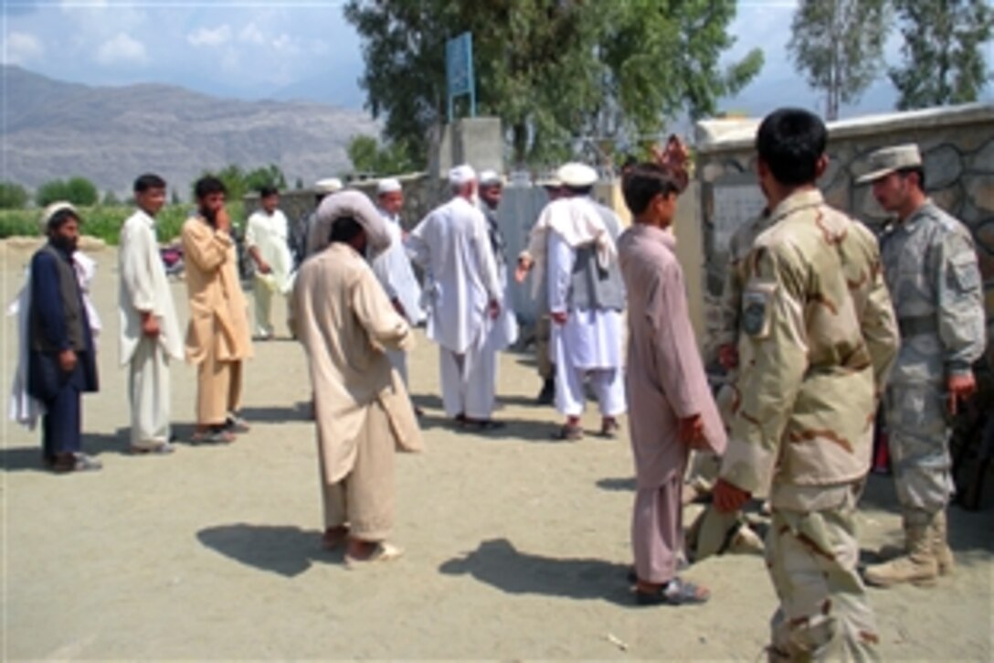 Afghans wait in line to vote as Afghan police provide security shortly after a polling site opens in the Khas Kunar district in Kunar province, Afghanistan, Aug. 20, 2009. Afghans in the area participated in the nation’s second national election as they came to vote for their country’s president.