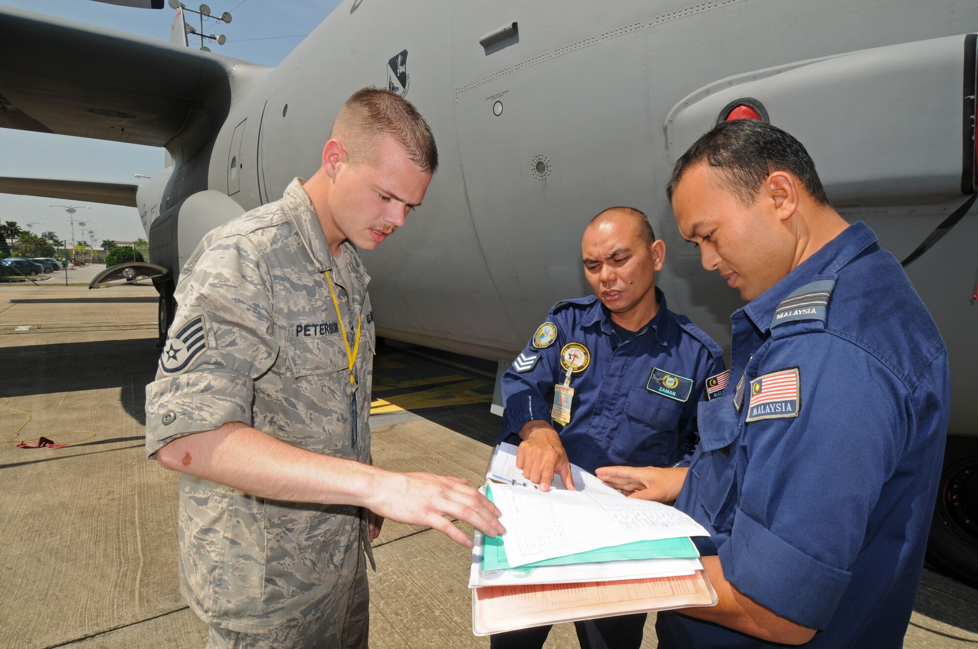 SUBANG ROYAL MALAYSIAN AIR FORCE BASE, Malaysia -- Staff Sgt. Neal Peterson, 374th Maintenance Squadron at Yokota Air Base, Japan, views C-130 technical forms with members of the Royal Malaysian Air Force Aug. 18 during the 2009 Pacific Airlift Rally here. The PAR is a biennial exercise involving Pacific Rim nations which enhances military airlift interoperability with a focus in humanitarian assistance and disaster relief operations. The exercise consists of a tabletop exercise and a field-training exercise involving three C-130 aircraft from the 374th Airlift Wing at Yokota Air Base, Japan, and one C-130 each from the Royal Malaysian Air Force, Royal Australian Air Force, Republic of Singapore Air Force and Royal New Zealand Air Force. (U.S. Air Force photo/Staff Sgt. Veronica Pierce)