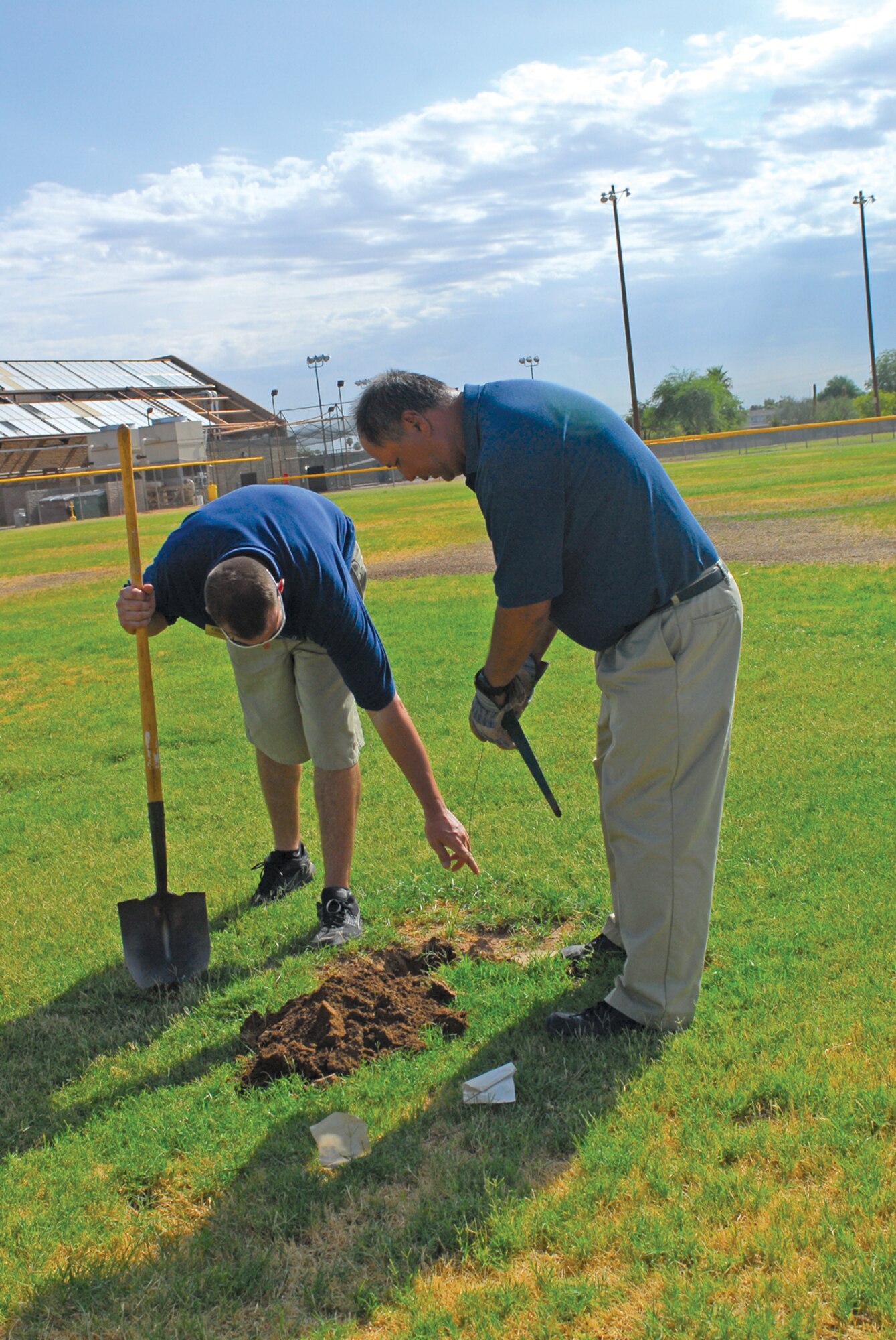 Chris Cohee, (left) Fitness Center equipment repairer and Jim Green, Fitness Center outdoor maintenance team member, set a gopher trap on a softball field at Luke Air Force Base. The team has caught 138 gophers since January of last year. 