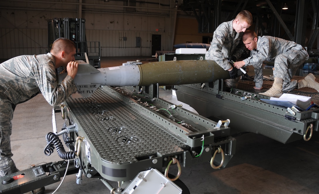 (Left to right) Airman John Baker, Airman 1st Class David Benner and Derrick Scott, 28th Munitions Squadron conventional maintenance crew members, work together while building a Guided Bomb Unit-38 here, August 20.  The GBU-38 is a 500-pound bomb which is commonly used with the B-1B Lancer. (U.S Air Force photo/Airman 1st Class Anthony Sanchelli)