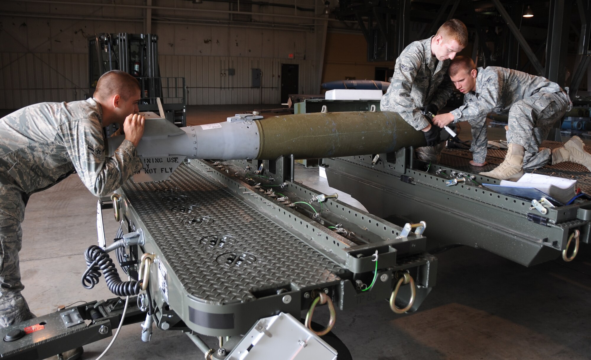(Left to right) Airman John Baker, Airman 1st Class David Benner and Derrick Scott, 28th Munitions Squadron conventional maintenance crew members, work together while building a Guided Bomb Unit-38 here, August 20.  The GBU-38 is a 500-pound bomb which is commonly used with the B-1B Lancer. (U.S Air Force photo/Airman 1st Class Anthony Sanchelli)
