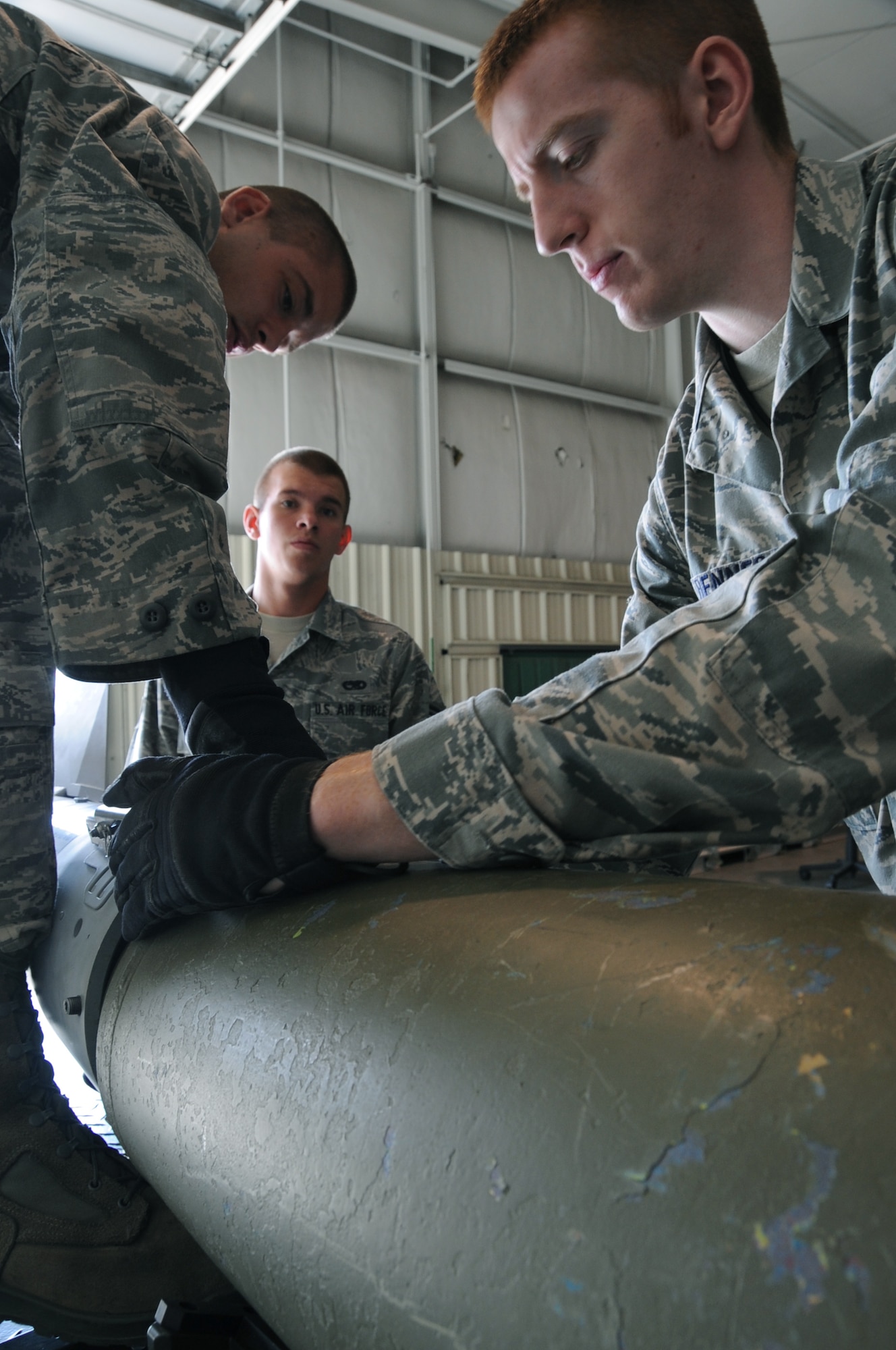 (Left to right) Airman John Baker, Airman 1st Class Derrick Scott and David Benner, 28th Munitions Squadron conventional maintenance crew members, team together to build a Guided Bomb Unit-38 here, August 20.  The GBU-38 is a 500-pound bomb which is commonly used in the B-1B Lancer's arsenal. (U.S Air Force photo/Airman 1st Class Anthony Sanchelli)