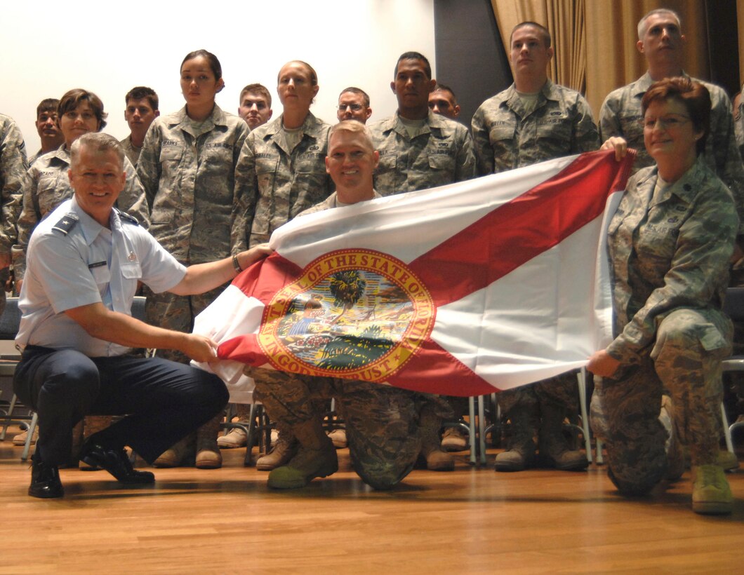 Florida Air National Guard Commander Brig. Gen. Joseph Balskus (left) and 290th JCSS Commander Lt. Col. Loretta Lombard (right) present a State of Florida flag to Maj. Rick Basting (center) and the deploying members of the 290th JCSS during a ceremony at MacDill Air Force Base, Aug. 16, 2009. Photo by Tech. Sgt. Thomas Kielbasa