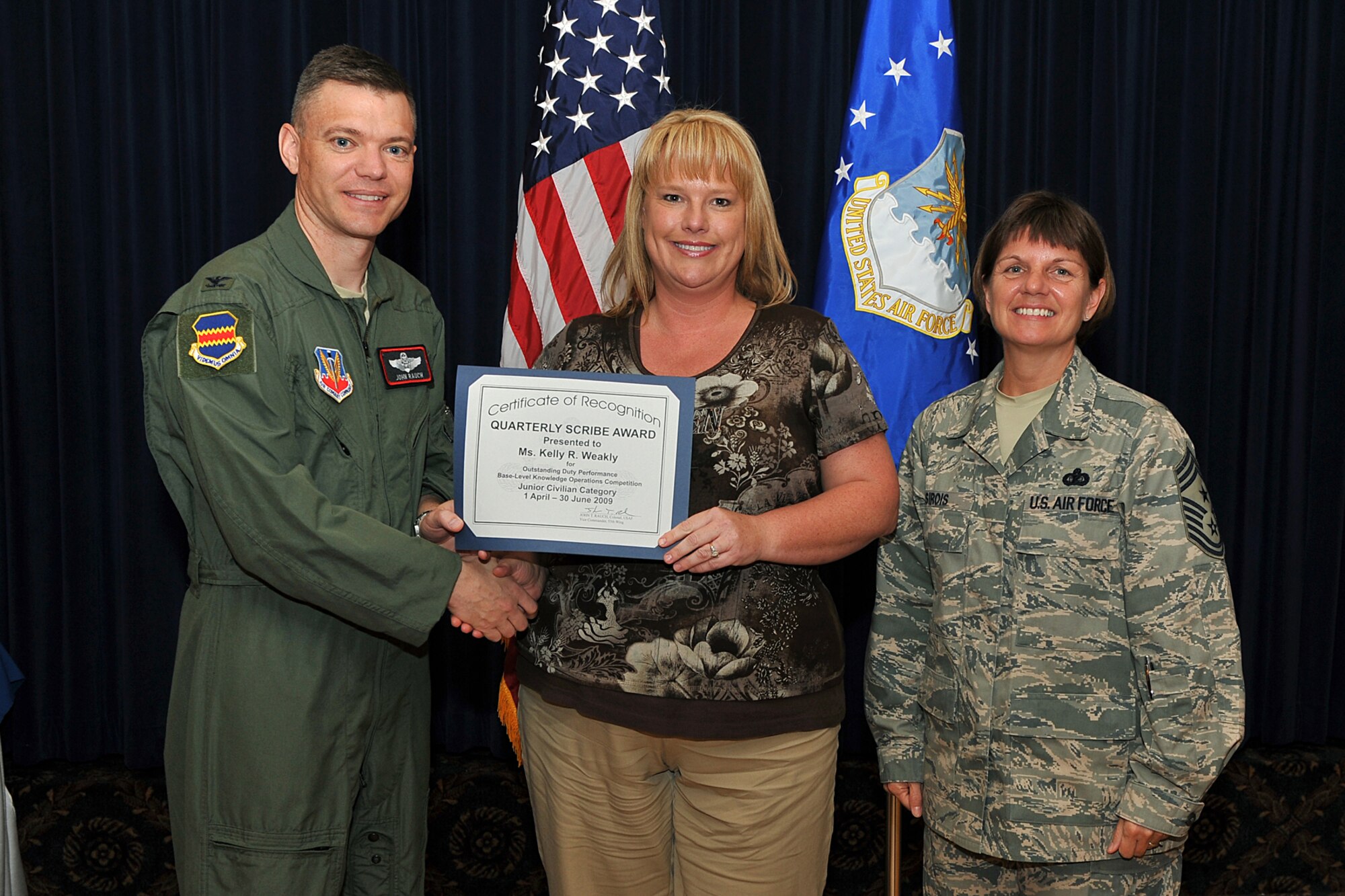 OFFUTT AIR FORCE BASE, Neb. -- Col. John T. Rauch, 55th Wing vice commander, presents Kelly Weakly, 55th Maintenance Group, with the scribe award for the civilian category as Chief Master Sgt. Lisa A. Sirois, 55th Wing command chief, looks on during the second quarter scribe awards luncheon at the Patriot Club Aug. 12. U.S. Air Force Photo by Charles Haymond