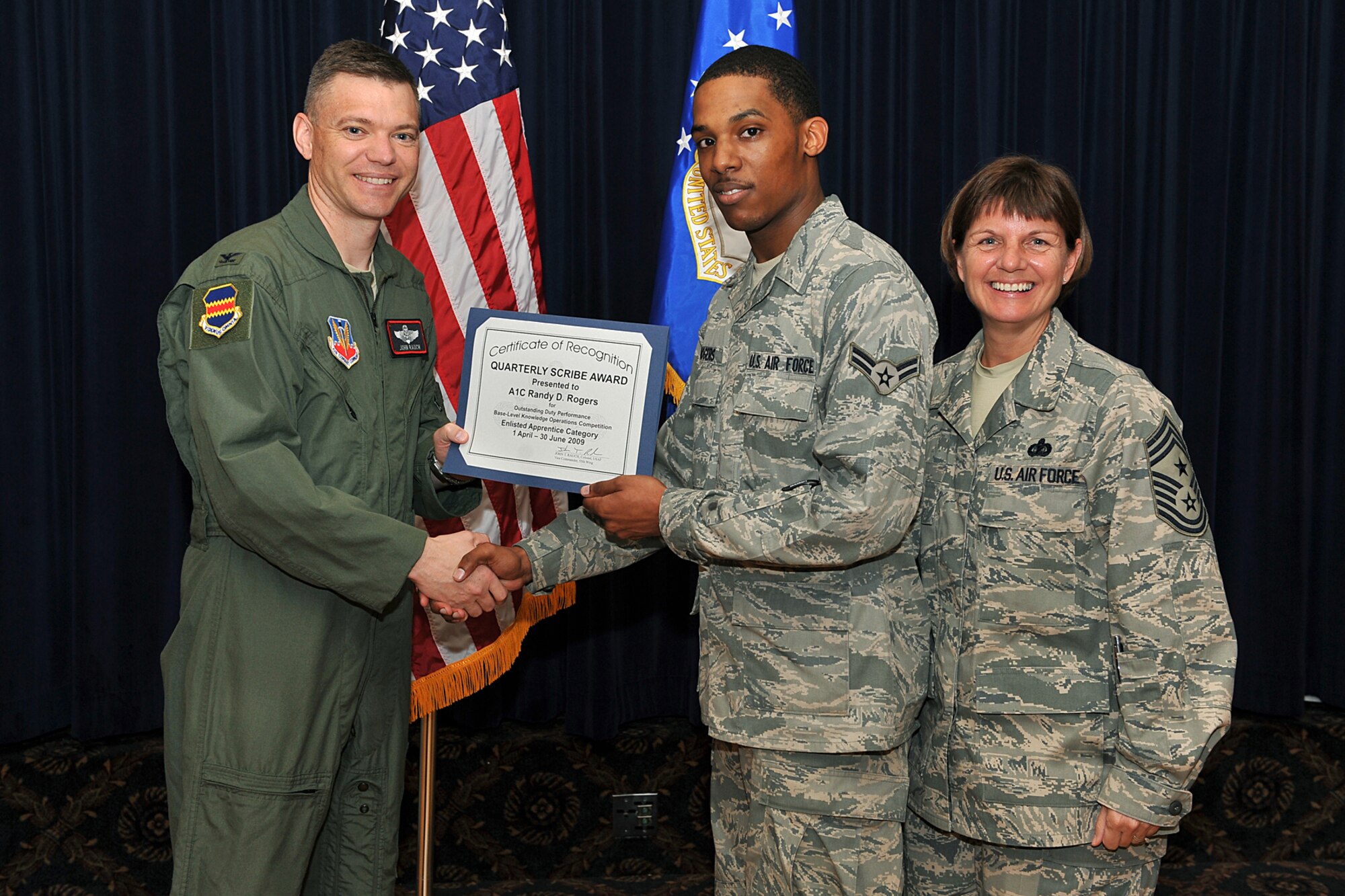 OFFUTT AIR FORCE BASE, Neb. -- Col. John T. Rauch, 55th Wing vice commander, presents Airman 1st Class Randy D. Rogers, 55th Communications Group, with the enlisted scribe award in the Airman category as Chief Master Sgt. Lisa A. Sirois, 55th Wing command chief, looks on during the second quarter scribe awards luncheon at the Patriot Club Aug. 12. U.S. Air Force Photo by Charles Haymond
