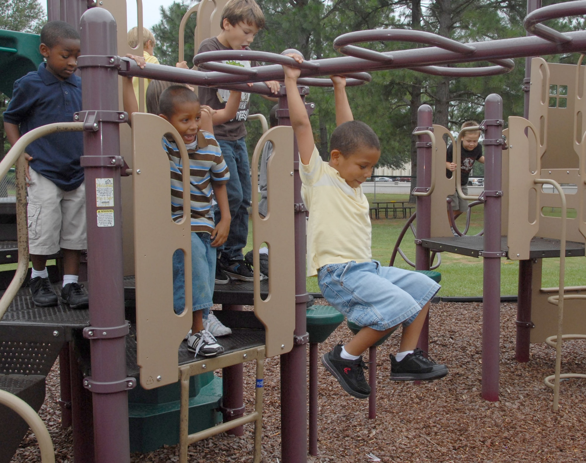 Children at the Gunter School Age Center enjoy the outdoor play equipment while Daylan Lowe tests his skills on the monkey bars. (U.S. Air Force photo/Roger Curry)