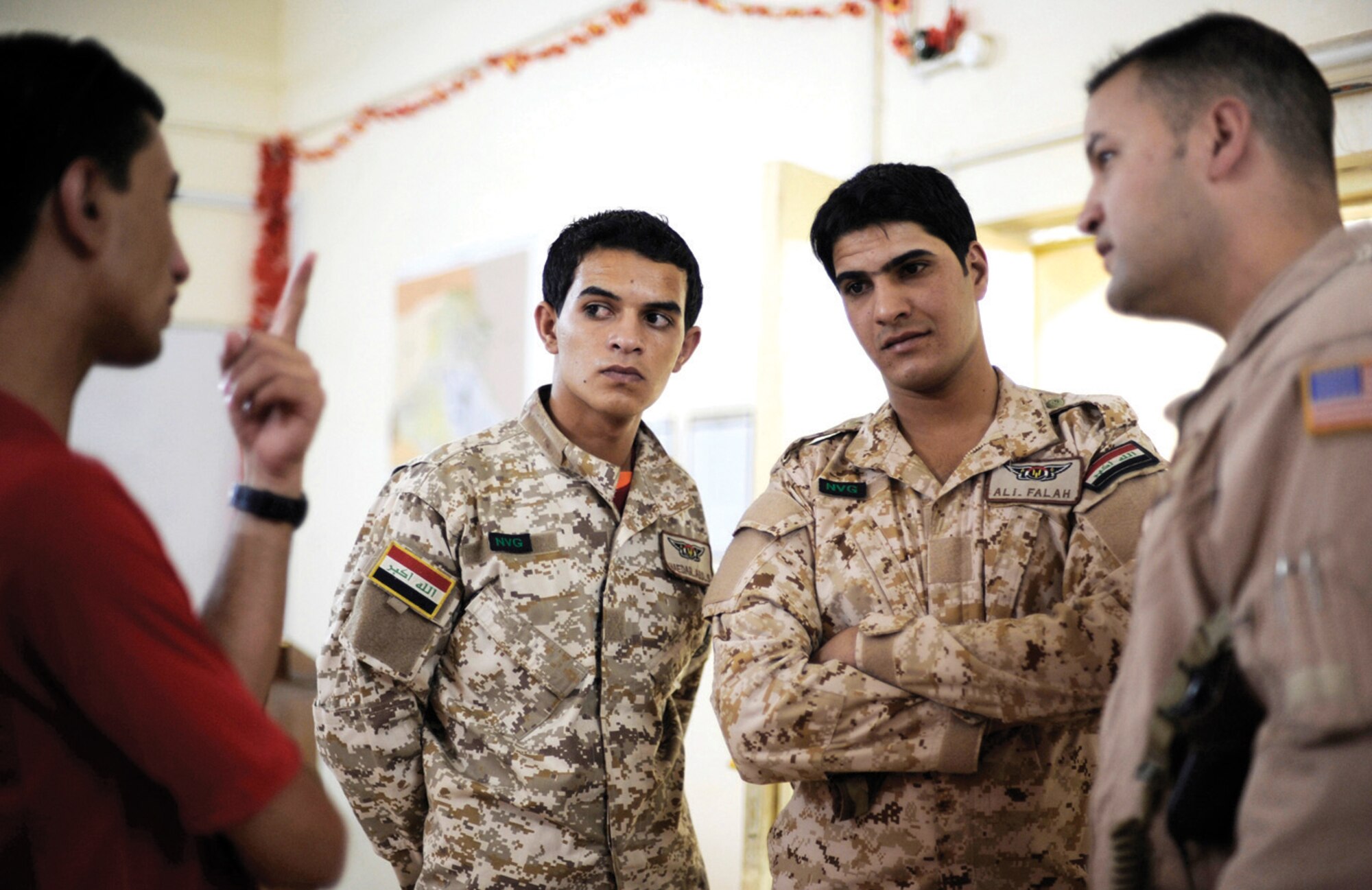 Technical Sgt. Onnez Rodriquez-Massas, 1st Helicopter Squadron special missions flight engineer, far right, speaks through an interpreter to two Iraqi air force aerial gunners prior to a night mission July 12 at Camp Taji, Iraq. Sergeant Rodriguez-Massas is an aerial gunner and Team Andrews member assigned to the 721st Air Expeditionary Advisor Squadron. (U.S. Air Force photo/ Staff Sgt. Michael B. Keller)