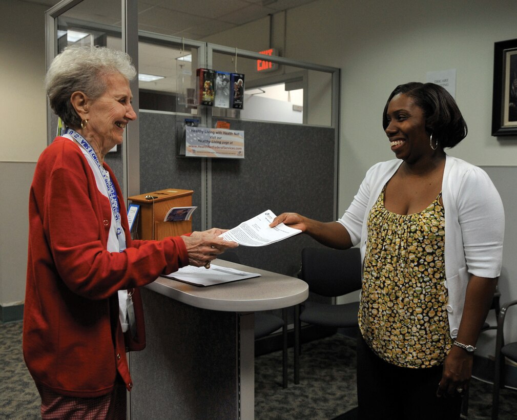 Betty Rankin, a retired dependent and volunteer at Malcolm Grow Medical Center, turns in her TRICARE paperwork to Nijeri Watkins at the TRICARE service counter Tuesday at MGMC. The paperwork ensures that Ms. Rankin can continue receiving care from her primary care manager. The new TRICARE policy states that anyone who lives more than a 30 minute drive from their PCM must sign a waiver to continue receiving their care from them. For more information on the policy, see the Retiree Corner on page 4. (U.S. Air Force photo/ Staff Sgt. Renae Kleckner)