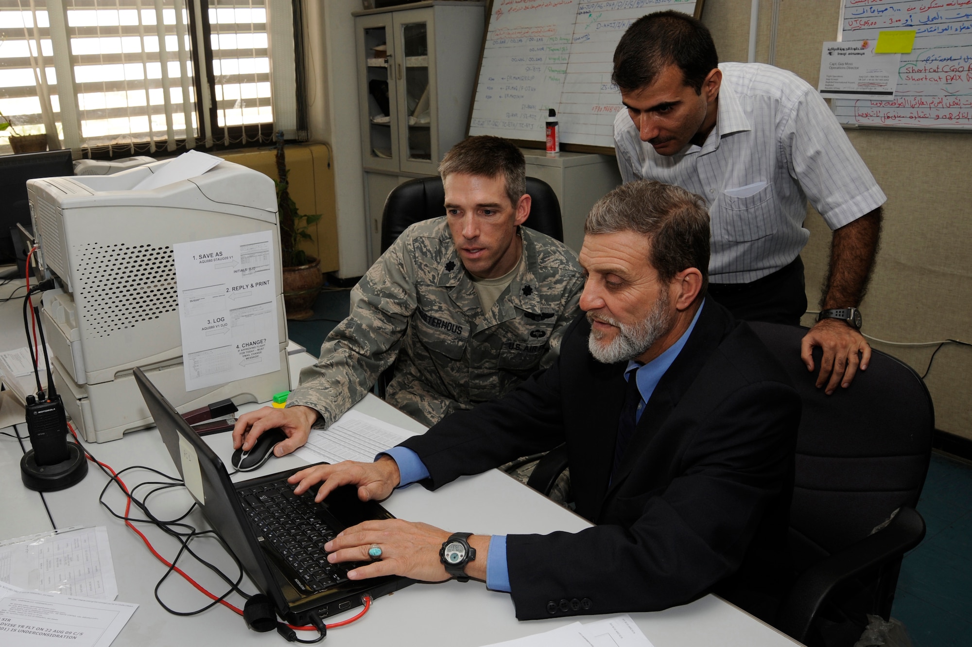 BAHGDAD -- Lt. Col. Dan Oosterhous, Regional Air Movement Control Center chief assigned to the Combined Air Operations Center in Southwest Asia, observes while members of the Iraqi Civil Aviation Authority here demonstrate their ability to properly approve and disapprove civil aircraft flights throughout Iraq Aug. 20, 2009. Colonel Oosterhous spent  60 days teaching the Iraqis to organize and archive their information on computer systems and use computer networks to process more than 400 daily flight requests and distribute a schedule to all aircraft command and control agencies throughout Iraq. Colonel Oosterhous is deployed from Scott Air Force Base, Ill., and is a native of Texarkana, Ark. (U.S. Air Force photo/Tech. Sgt. Johnny L. Saldivar/Released) 