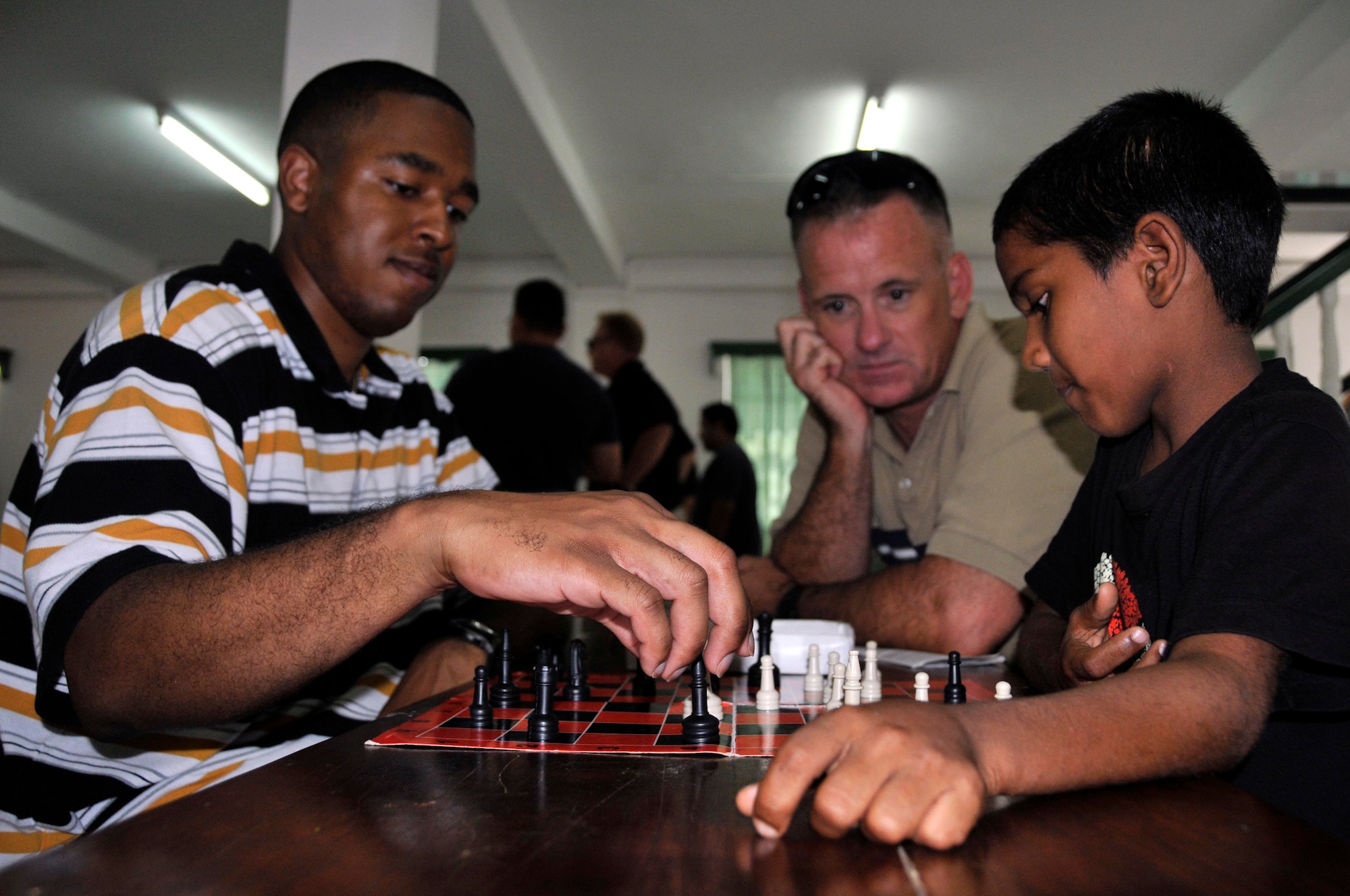 Col. Douglas Galipeau, 474th Air Expeditionary Group Commander watches Sgt. Christopher Still plays chess with a Guyanese boy Aug 20, 2009, at Sad'r Boys Orphanage, Georgetown, Guyana. Col. Galipeau visited two Medical Readiness and Training Exercises, one Dental Readiness and Training Exercise, an orphanage, and two construction projects all part of New Horizons Guyana. (U.S. Air Force photo by Airman 1st Class Perry Aston) (Released)