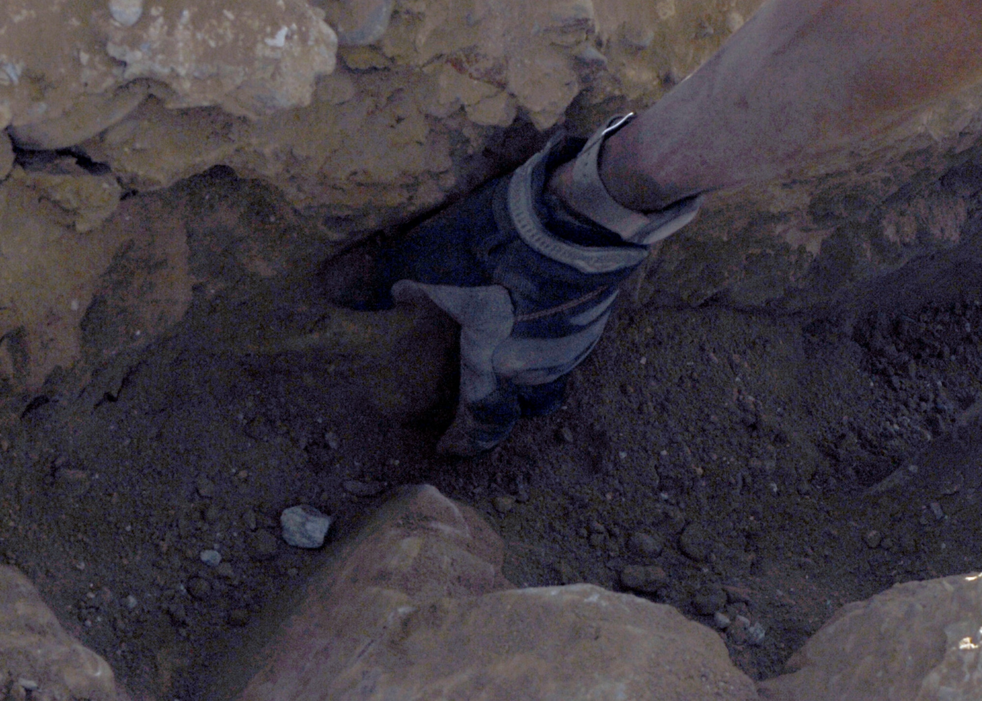 BAGRAM AIRFIELD, Afghanistan - Tech. Sgt. John Lowe III, from the 455th Expeditionary Communications Squadron, clears dirt away from a rock that he must remove here, Aug. 20. The machines used to dig the channels necessary for the job cannot cut through rocks this large, which then requires members to extract the rocks by hand. Sergeant Lowe is deployed from Ramstein Air Base, Germany and hails from Philadelphia. (U.S. Air Force photo/Senior Airman Felicia Juenke)