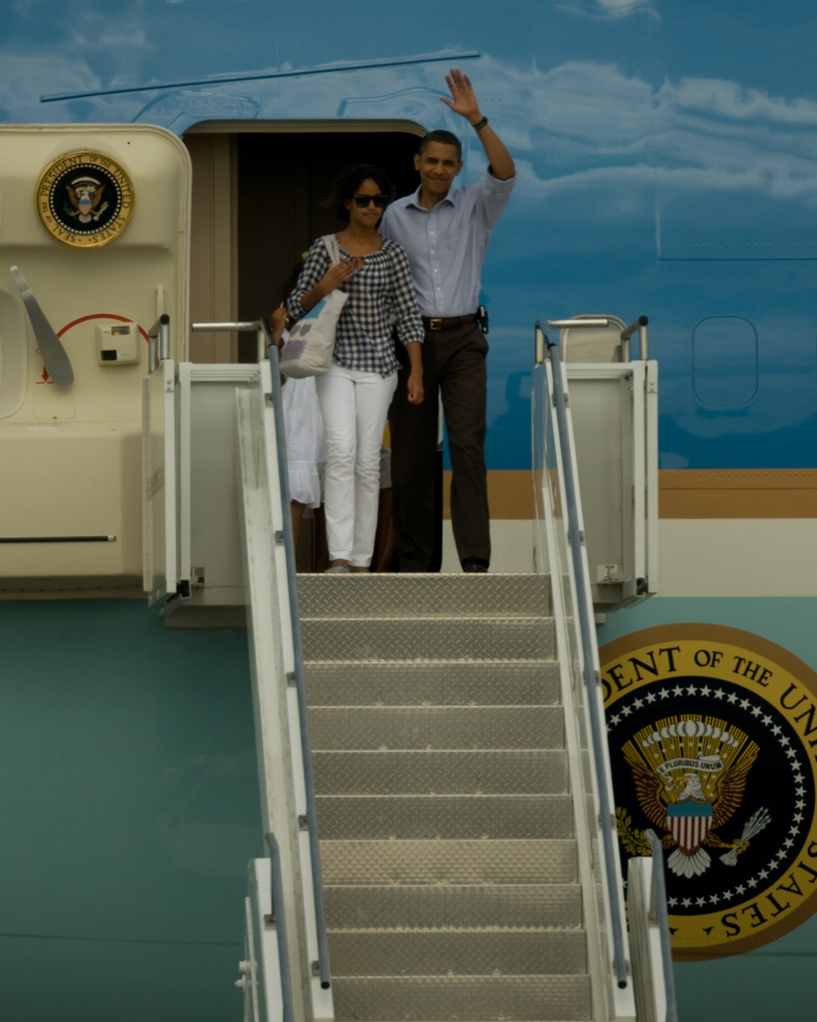 President Barack Obama emerges from Air Force One with a wave to the crowd and his daughter Malia at his side shortly after landing at the Massachusetts Military Reservation on Aug. 23, 2009. President Obama and The First Family landed at the MMR in Air Force One and within minutes boarded Marine One headed for a week-long vacation on Martha's Vineyard.