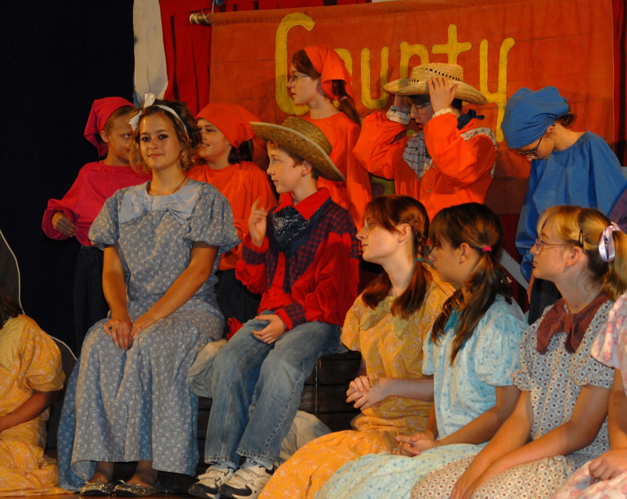Alisha Kalder, far left and Benjamin Ingalls, seated in red, wait to go through some lines during rehearsal for the  Beauty Lou and the Country Beast performance at the Goodfellow AFB base theater Aug. 14.  The Missoula Children's Theatre provides a week-long performance workshop and rehearsals that culminate in two full-scale musical public performances starring almost 60 Goodfellow youth.
 (U.S. Air Force / Robert D. Martinez)