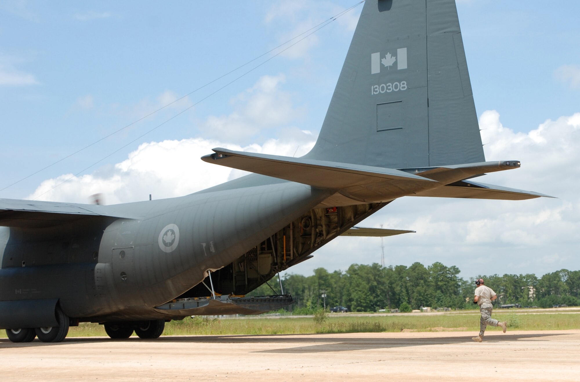 A member of the contingency response element from the 819th Global Support Squadron at Joint Base McGuire-Dix-Lakehurst, N.J., runs to a Canadian C-130 to help facilitate the off-loading of a pallet of MREs on Aug. 22, 2009, that were being delivered to the Army during the Joint Readiness Training Center Exercise 09-09 at Fort Polk, La. The JRTC provides realistic training using war-time scenarios that allow integration between joint military organizations, host nations and civilian role-players. Units from the Air Force, Army and from the Canadian and Belgian air forces are training together during the 09-09 exercise.  (U.S. Air Force Photo/Bekah Clark)