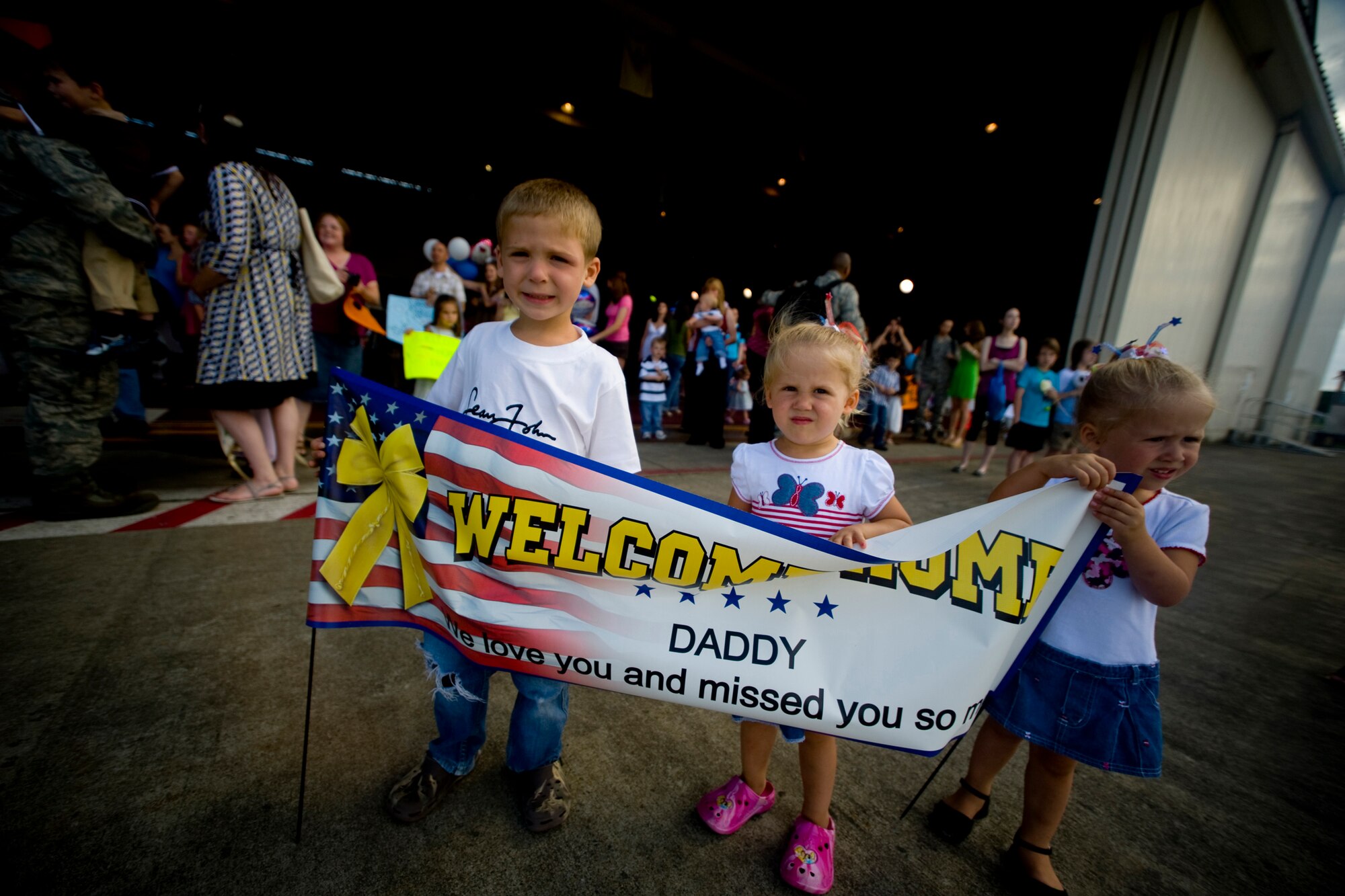 MISAWA AIR BASE, Japan -- Ayden, Savannah and Gretchen Davila await to greet their father, Tech Sgt. Yamil Davila, 13th Aircraft Maintenance Unit, Aug. 23.  Friends, family and co-workers gathered at Hangar 949 to greet the returning Airmen who deployed to Suwon Air Base, South Korea. (U.S. Air Force photo/Senior Airman Jamal D. Sutter)