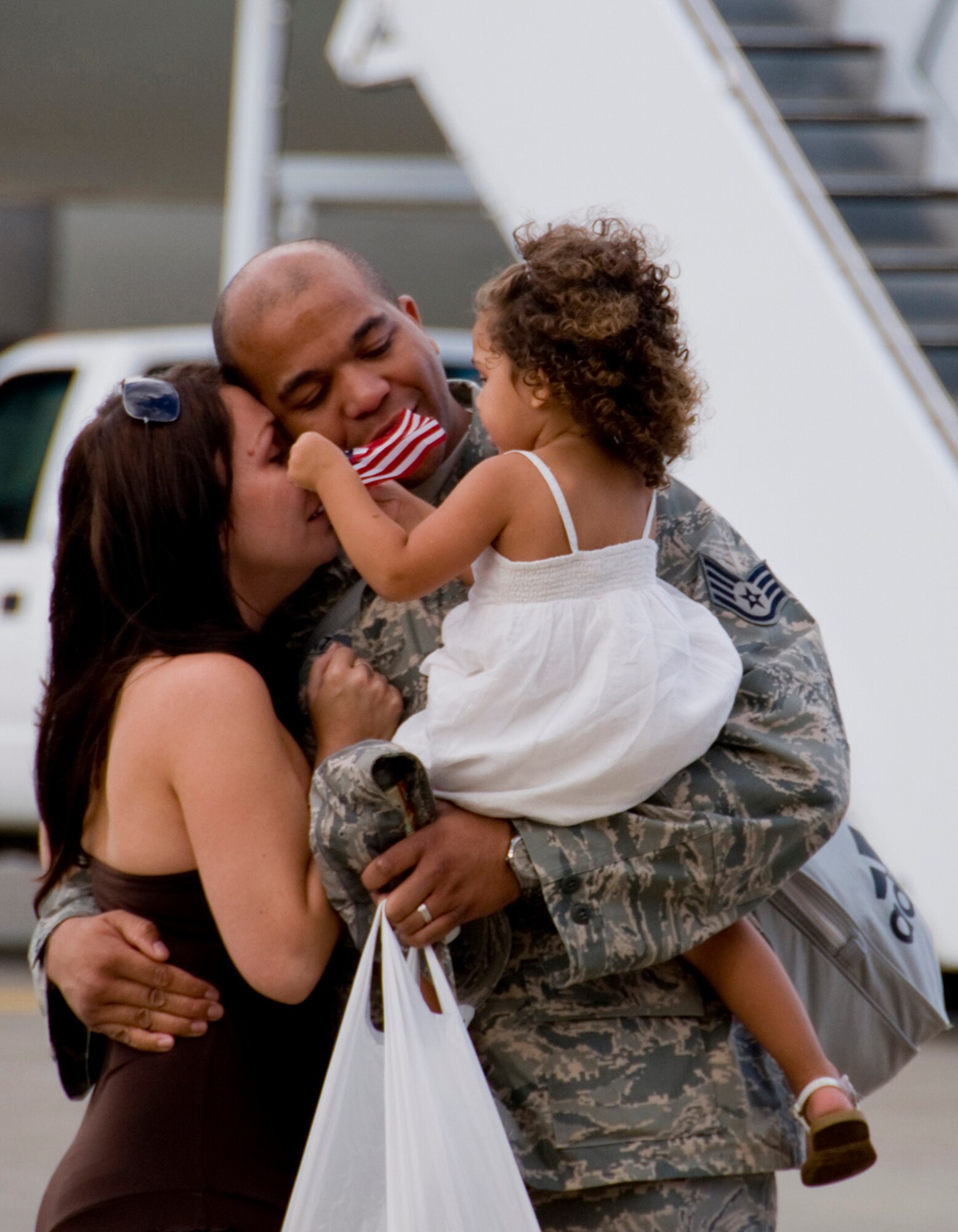 MISAWA AIR BASE, Japan -- Staff Sgt. Christopher Stewart, 35th Maintenance Squadron, embraces his wife, Kelly, and daughter, Morgan, after returning from deployment Aug. 23. Sergeant Stewart, along with more than 200 others, supported the 13th Fighter Squadron during a deployment to Suwon Air Base, South Korea. (U.S. Air Force photo/Senior Airman Jamal D. Sutter)