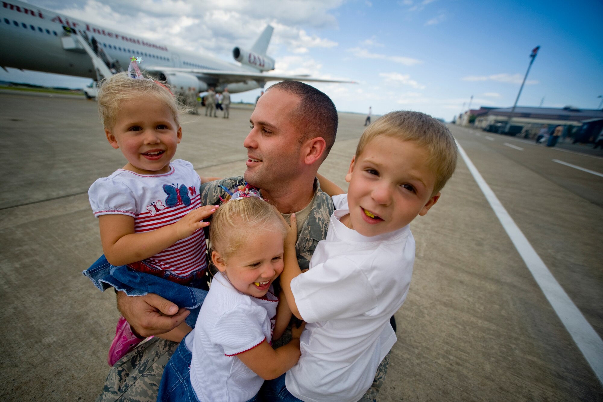 MISAWA AIR BASE, Japan -- Tech. Sgt. Yamil Davila, 13th Aircraft Maintenance Unit, hugs his son and daughters, Ayden, Savannah and Gretchen, after returning from deployment Aug. 23. Sergeant Davila, along with members of his unit, supported the 13th Fighter Squadron during a six-month deployment to Suwon Air Base, South Korea. (U.S. Air Force photo/Senior Airman Jamal D. Sutter)
