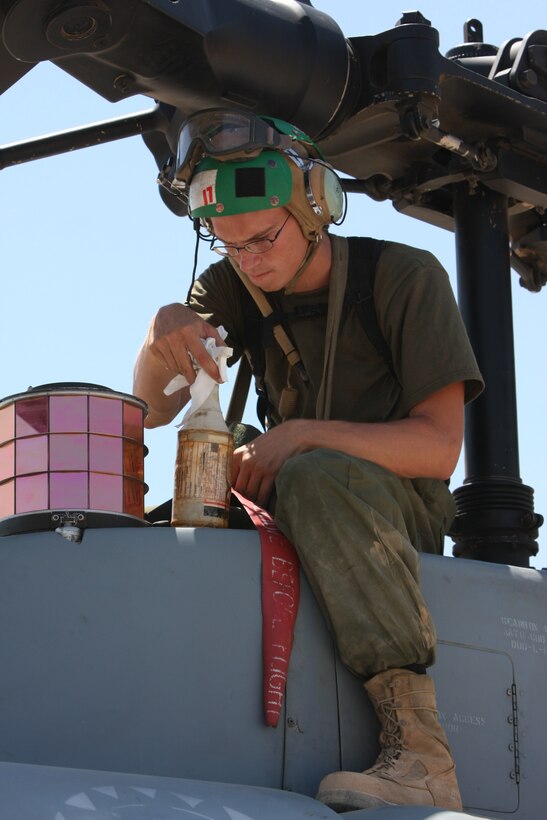 Lance Cpl. Ethan Schreffler, an aircraft communications, navigation, electrical and weapon systems technician with Marine Light Attack Helicopter Squadron 367, cleans a UH-1 Yankee Super Huey Helicopter missile counter measure system at the Combat Center's Prospect training area Aug. 25.