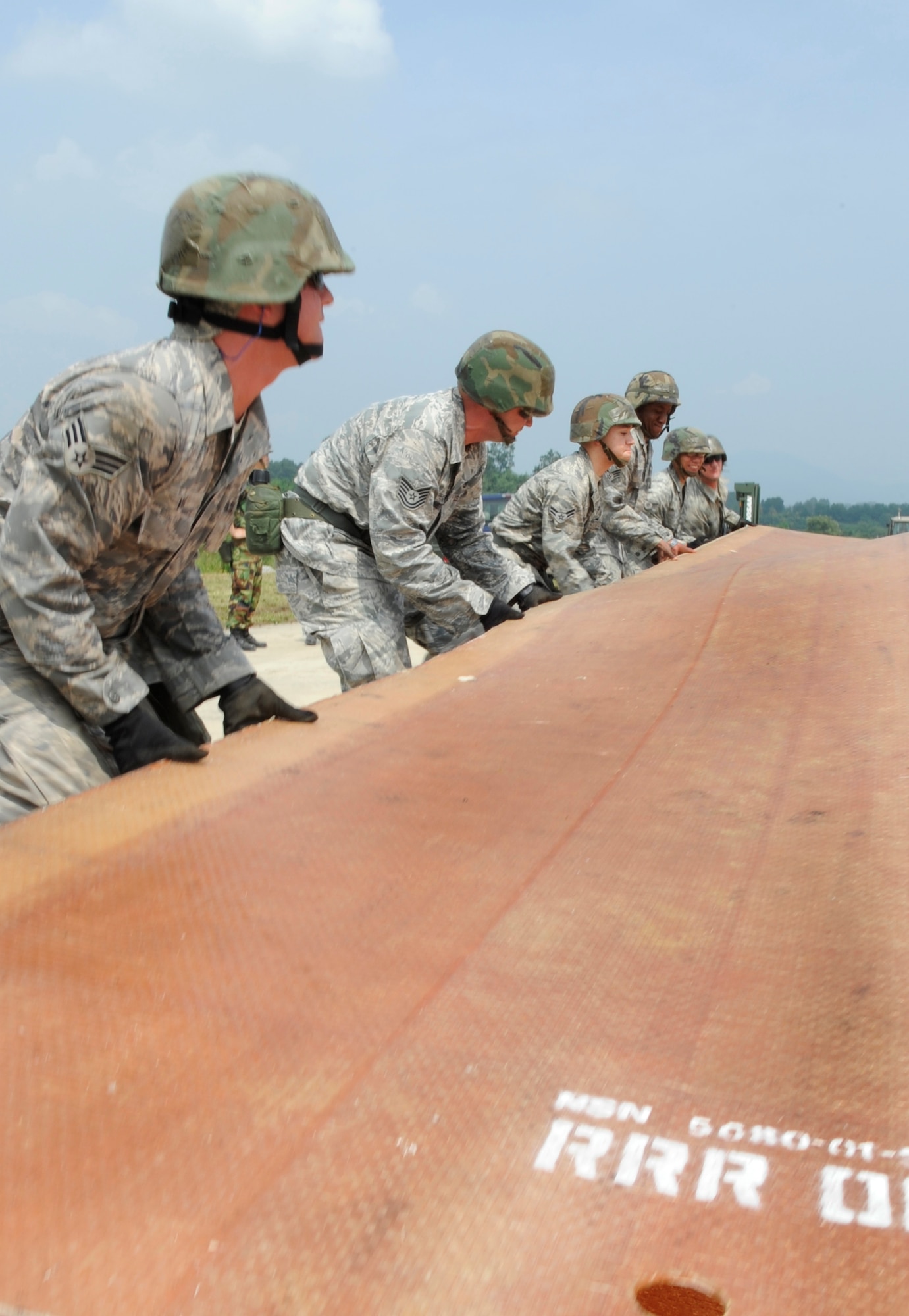 Airmen from the 51st Civil Engineer Squadron unfold a fiberglass mat on the simulated runway before it is put into place at Jungwon Air Base, Republic of Korea Aug 19. The 30-foot long, 54-foot wide foot mats are used to quickly repair runway damage, and can be connected to cover a large area. The mats are being moved as part of a joint combined rapid runway repair training exercise with Airmen from the Republic of Korea Air Force's 19th Tactical Fighter Wing and 91st Air Civil Engineer Group.  The 51st CES is assigned to Osan Air Base, Republic of Korea. (U.S. Air Force photo/Senior Airmen Stephenie Wade)
