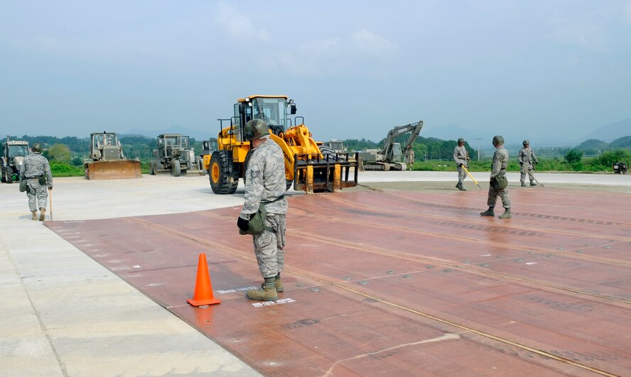 Airmen from the 51st Civil Engineer Squadron stand on a folded fiberglass mat as it is moved into place by a 10,000-pound forklift on a simulated runway at Jungwon Air Base, Republic of Korea, Aug. 19. The 30-foot long, 54-foot wide mats are used to quickly repair runway damage, and can be connected to cover a large area. The mats are being moved as part of a joint combined rapid runway repair training exercise with Airmen from the Republic of Korea Air Force's 19th Tactical Fighter Wing and 91st Air Civil Engineer Group.  The 51st CES is assigned to Osan Air Base, Republic of Korea. (U.S. Air Force photo/Senior Airmen Stephenie Wade)
