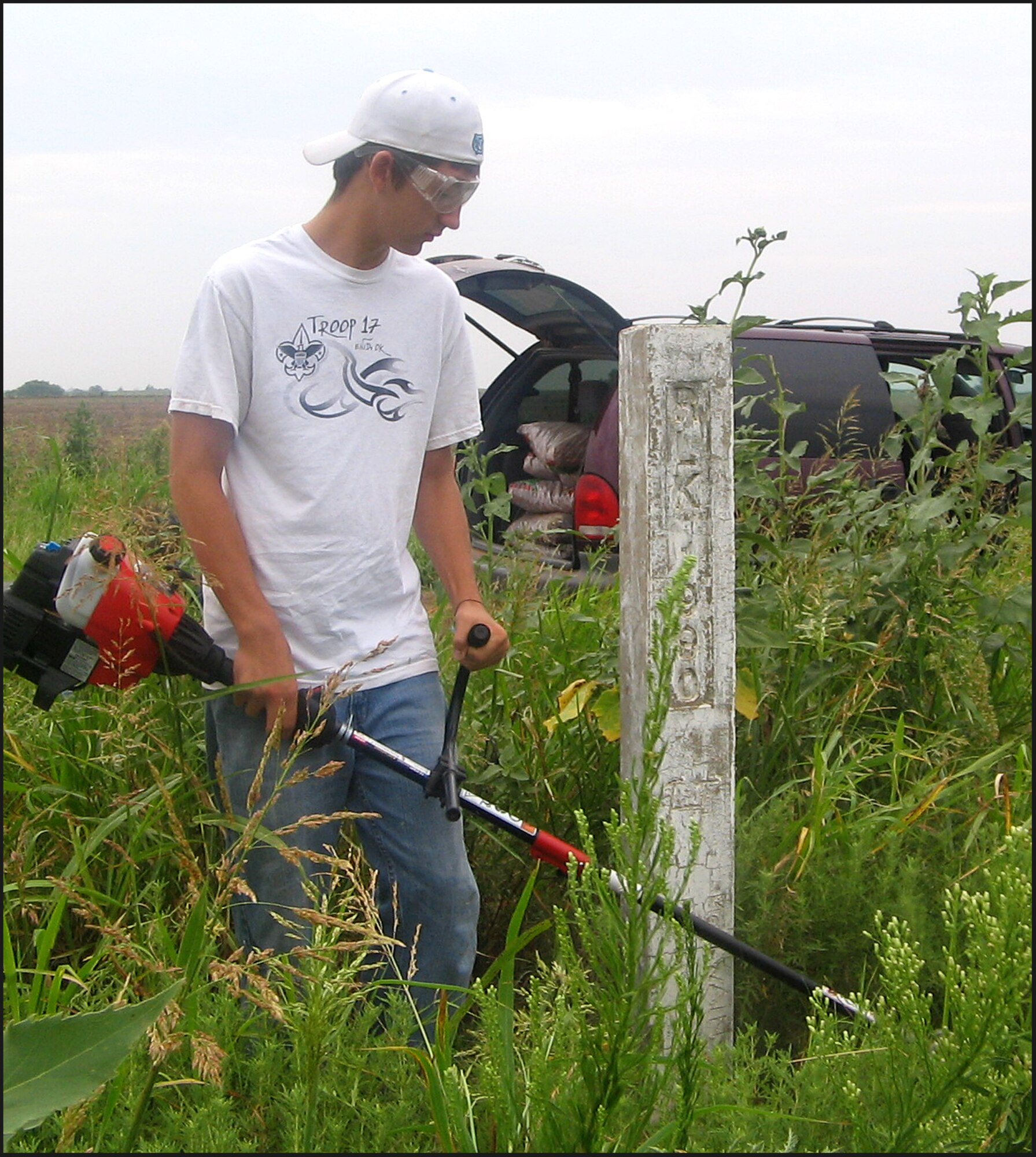 Andy Pyper clears weeds away from one of 28 Chisholm Trail markers that follow the historical cattle-drive route through Grant County, Okla. Andy, son of Maj. Vaughn Pyper of the 25th Flying Training Squadron at Vance AFB, organized the service project to fulfill a requirement for Eagle Scout. Grant County is north of Garfield County where Vance AFB is located. (Photo by Liesl Maloy)
