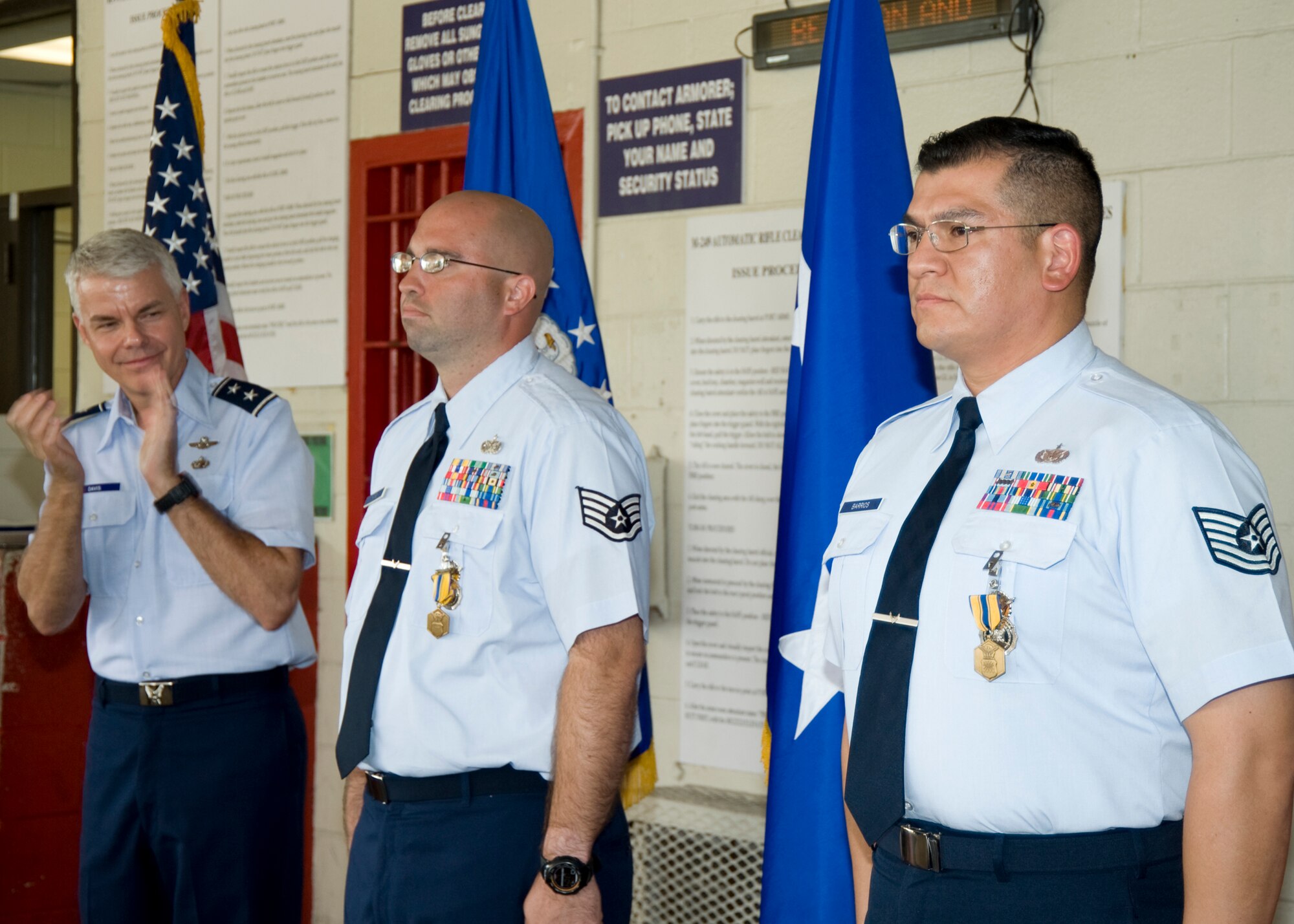 Staff Sgt. Gary King Jr. and Tech Sgt. Hector Barrios, 96th Security Forces Squadron, receive applause from Maj. Gen. C.R. Davis, Air Armament Center commander, and other squadron members in attendance at their award ceremony Aug. 24.  Both NCOs received Air Force commendation medals from the general for acts of courage in the line of duty.  U.S. Air Force photo /Debbie Haussermann.)