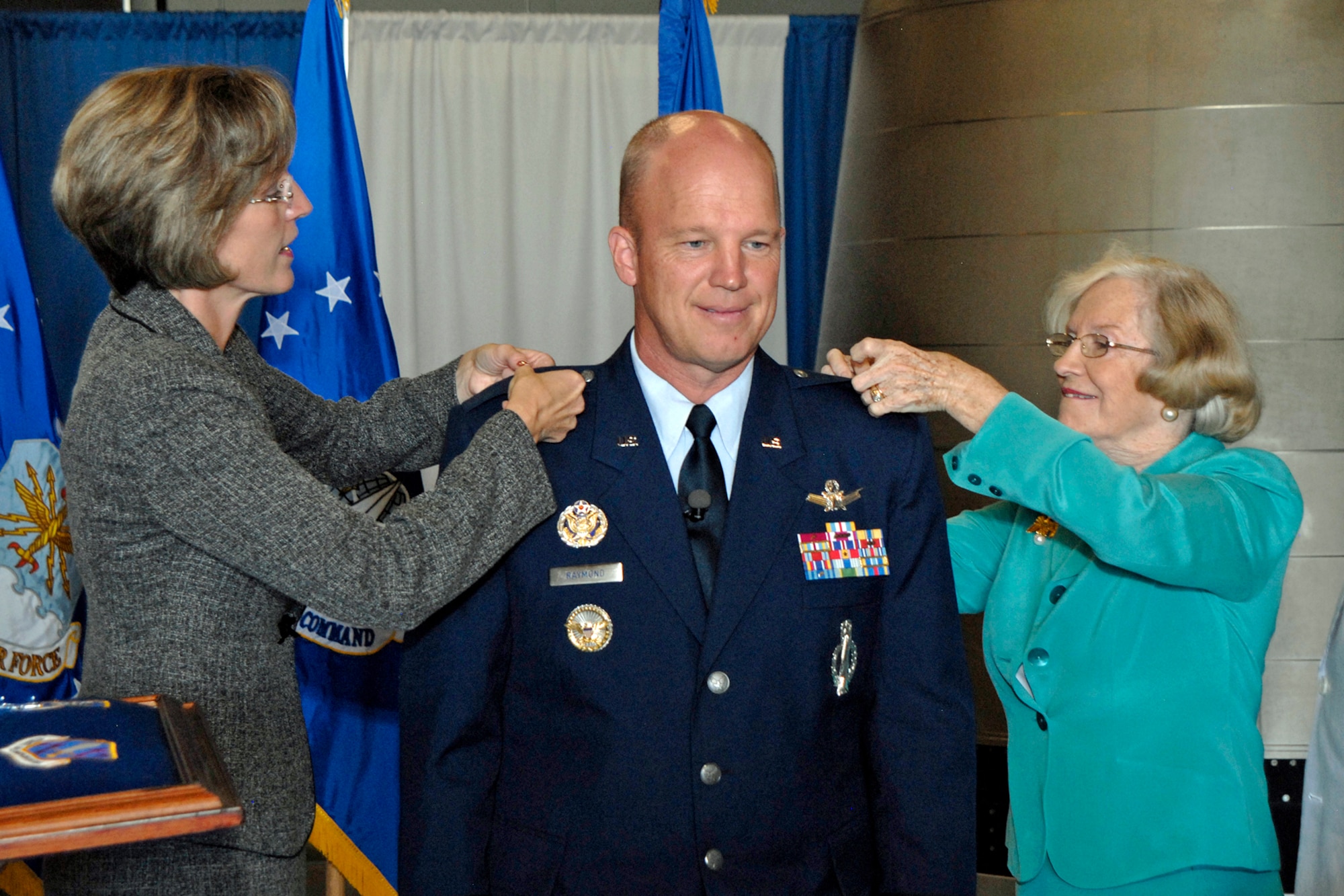 PETERSON AIR FORCE BASE, Colo. -- Mollie Raymond (left), wife of Brig. Gen. Jay Raymond, and Ms. John Raymond (right), General Raymond’s mother, pin on his first star Aug. 21 in a promotion ceremony held at Peterson Air and Space Museum. In a change of command ceremony held Aug. 20, General Raymond relinquished command of the 21st Space Wing to Col. Stephen Whiting, to assume the duties of director of plans, programs and analyses at Headquarters Air Force Space Command. (Air Force photo by Craig Denton)