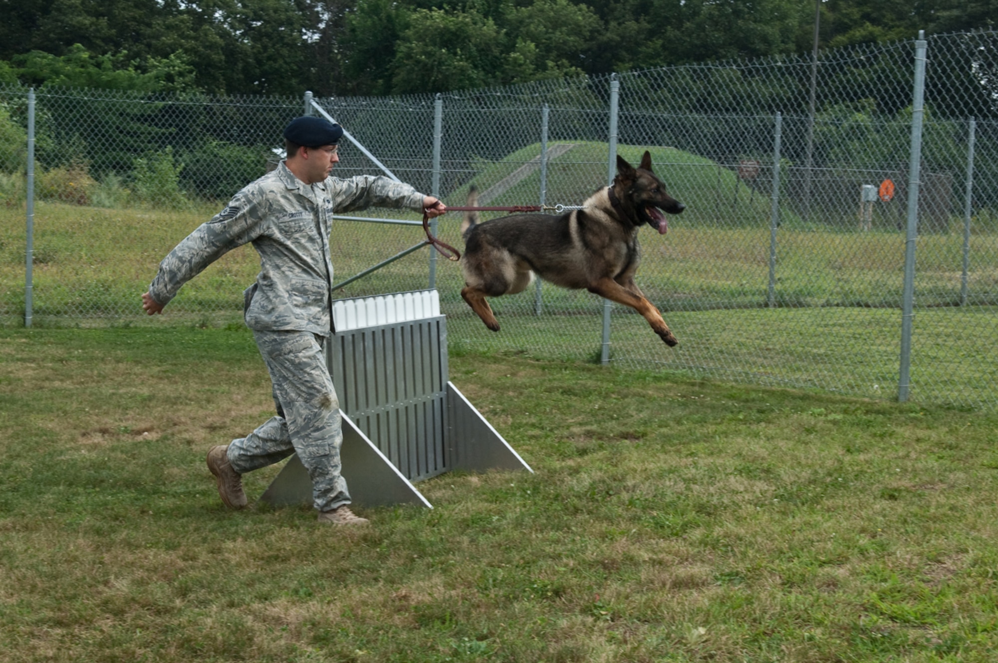 HANSCOM AIR FORCE BASE, Mass. –Staff Sgt. Richard Crotty, 66th Security Forces Squadron, puts Military Working Dog Boxi through some training exercises Aug. 21. Security Forces personnel recently installed a new obstacle course to enhance the training and conditioning for Hanscom’s Military Working Dogs.  (U.S. Air Force photo by Rick Berry) 