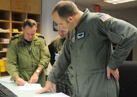 Canadian Air Force Maj. Andy Cleveland discusses flight plans with Capt. Steve Churchill, 326th Airlift Squadron aircraft commander, and Capt. Dan Zappe, 326th AS pilot, Aug. 23 at 8 Wing Canadian Forces Base Trenton, which is two miles northeast of Trenton, Ontario. The 326th AS flew there Aug. 22-24 with members of the 46th Aerial Port, 512th Airlift Control Flight and 712th Aircraft Maintenance Squadron to meet with members of the 429 Transport Squadron and 2 Air Movements Squadron to identify future training opportunities. (U.S. Air Force photo/Capt. Marnee A.C. Losurdo)