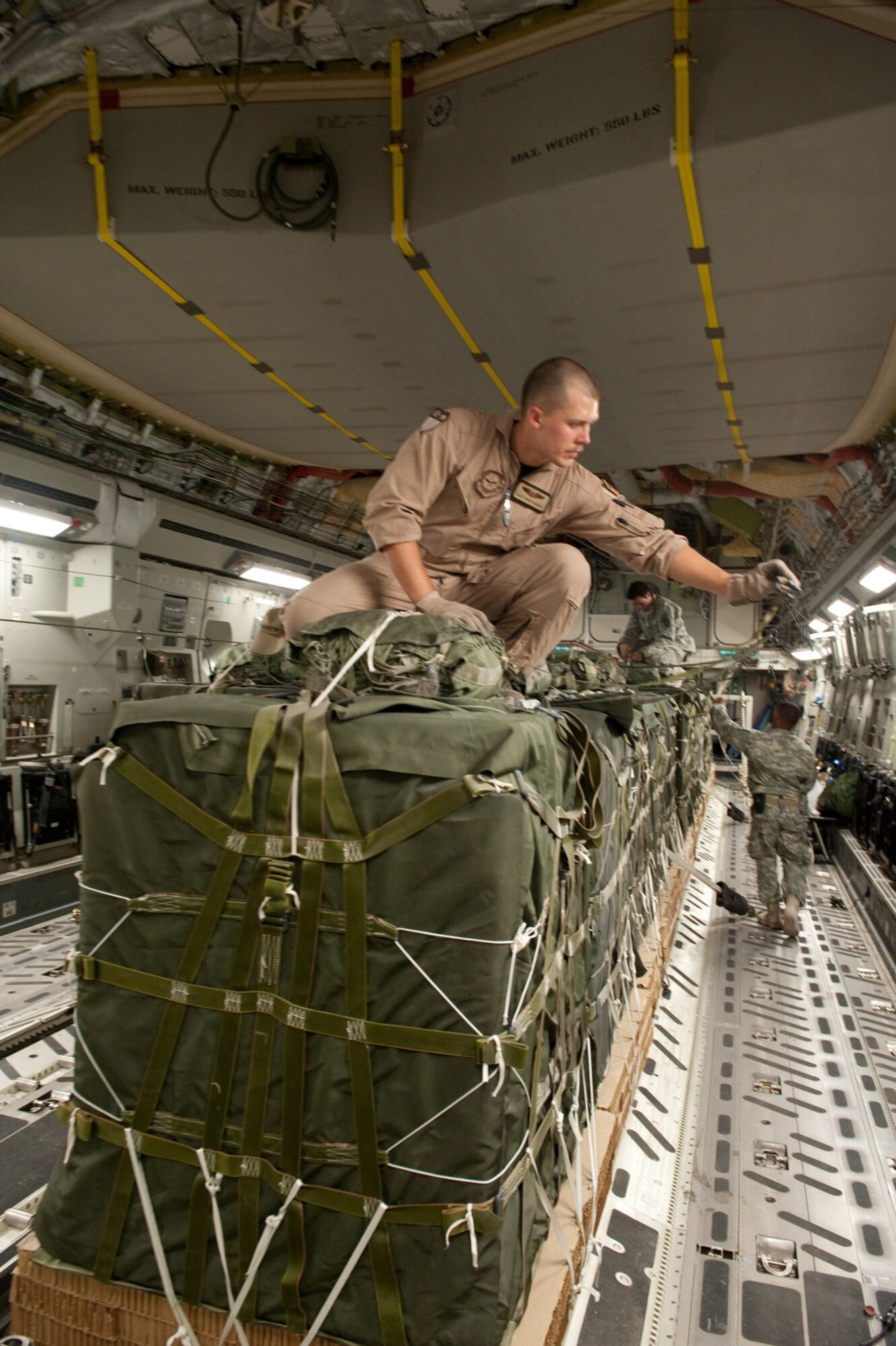 Staff Sergeant Chris Baker, 817th Expeditionary Airlift Squadron loadmaster, secures an aerial drop load static line, Aug. 12, on a C-17 Globemaster III in Southwest Asia. The cargo will be air dropped to military servicemembers throughout the U.S. Central Command area of responsibility.  Sergeant Baker is deployed from McChord Air Force Base, Wash., in support of Operations Iraqi and Enduring Freedom. (U.S. Air Force Photo/Staff Sgt. Robert Barney)