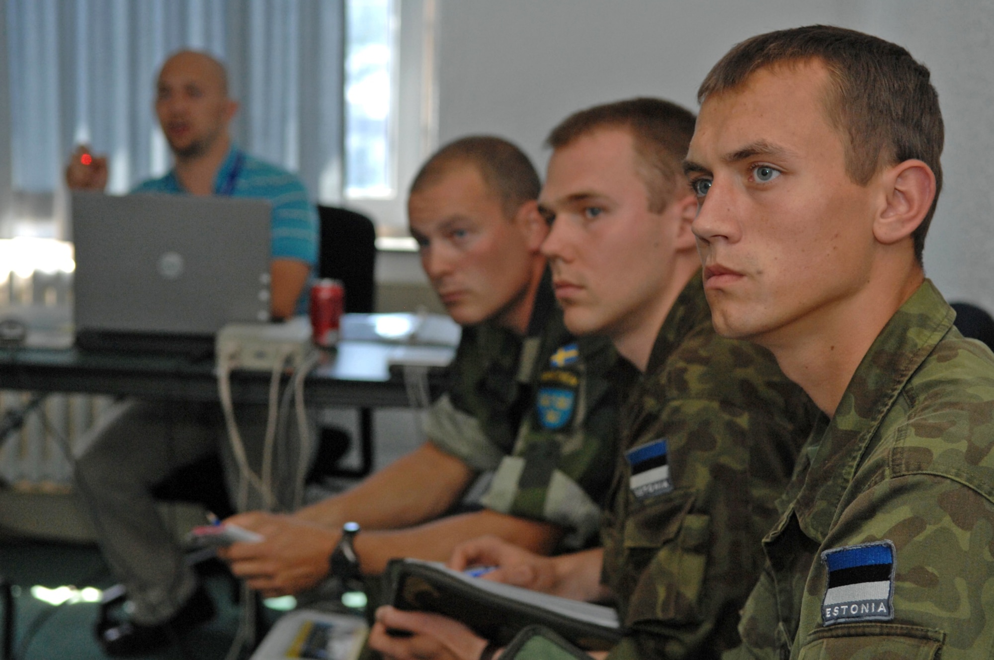 Estonian air force members Junior Sergeant David Mellov, 2nd Lt. Evo Koiv and Swedish army ranger Capt. Timothy Walsh watch a demonstration of a computer simulator at the U.S. Air Forces in Europe Air Ground Operations School used for practicing air strikes during close-air-support operations. The forward air controllers spent a week in pre-deployment briefings, computer simulation, and field training prior to deployment thanks to the joint efforts of the staff at the USAFE AGOS and the International Security Assistance Force Cell at NATO Allied Air Component Command Headquarters Ramstein Aug. 17- 21. (U.S. Air Force photo/Master Sgt. Corey Clements)